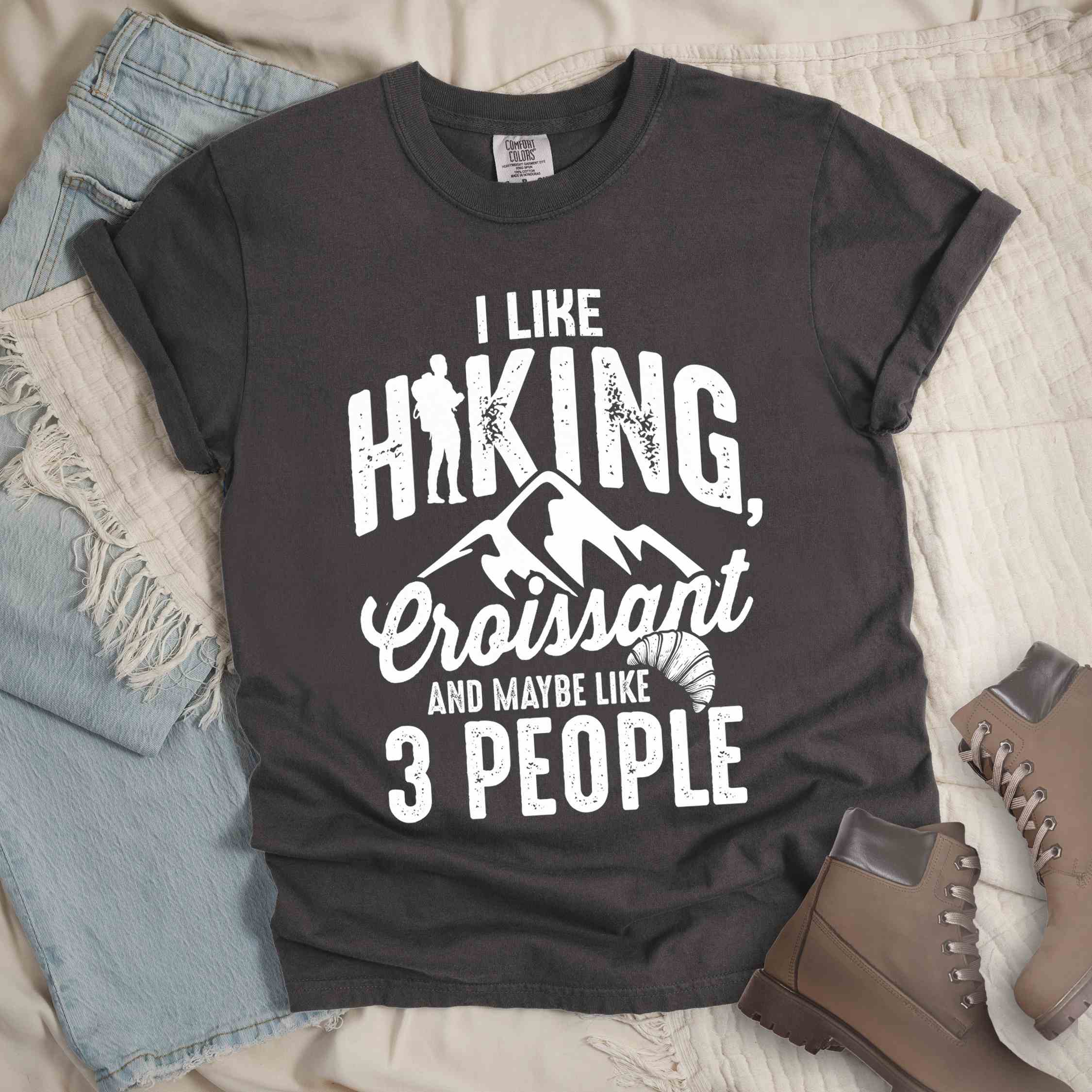 Pepper "I Like hiking, croissant and maybe like 3 people" colored vintage tee with bold typography, birds, mountains, illustrated croissant, and backpacker for pastry enthusiasts.