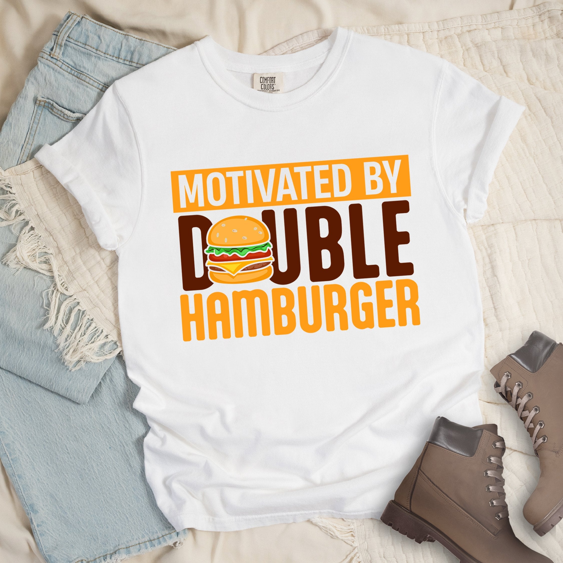 White shirt with Hiking Design featuring the phrase “Motivated by Double Hamburger” and an illustration of a cartoon-style double hamburger between the words.