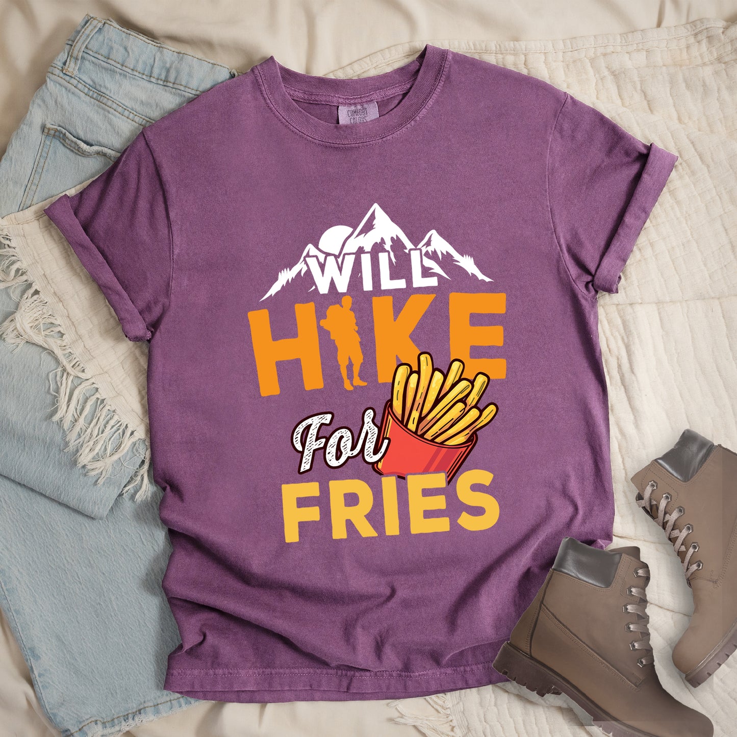 Berry (Dark Violet) t-shirt with text "WILL HIKE For FRIES". White mountain silhouettes appear above "WILL" in white letters. "HIKE" is in large orange letters with a hiker silhouette replacing the letter "I". "For" appears in white script, and "FRIES" in yellow at the bottom. Next to "For" and above "FRIES" is an illustration of french fries in a red container. The design combines hiking motivation with food rewards.
