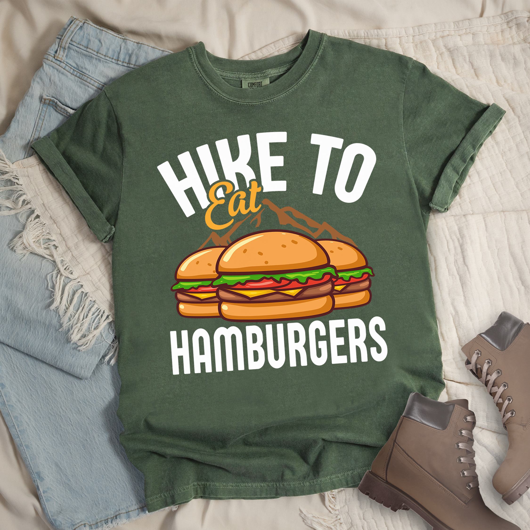 Dark green shirt with Hiking Design featuring the phrase “Hike to Eat Hamburgers” and an illustration of two hamburgers placed in front of mountain outlines.