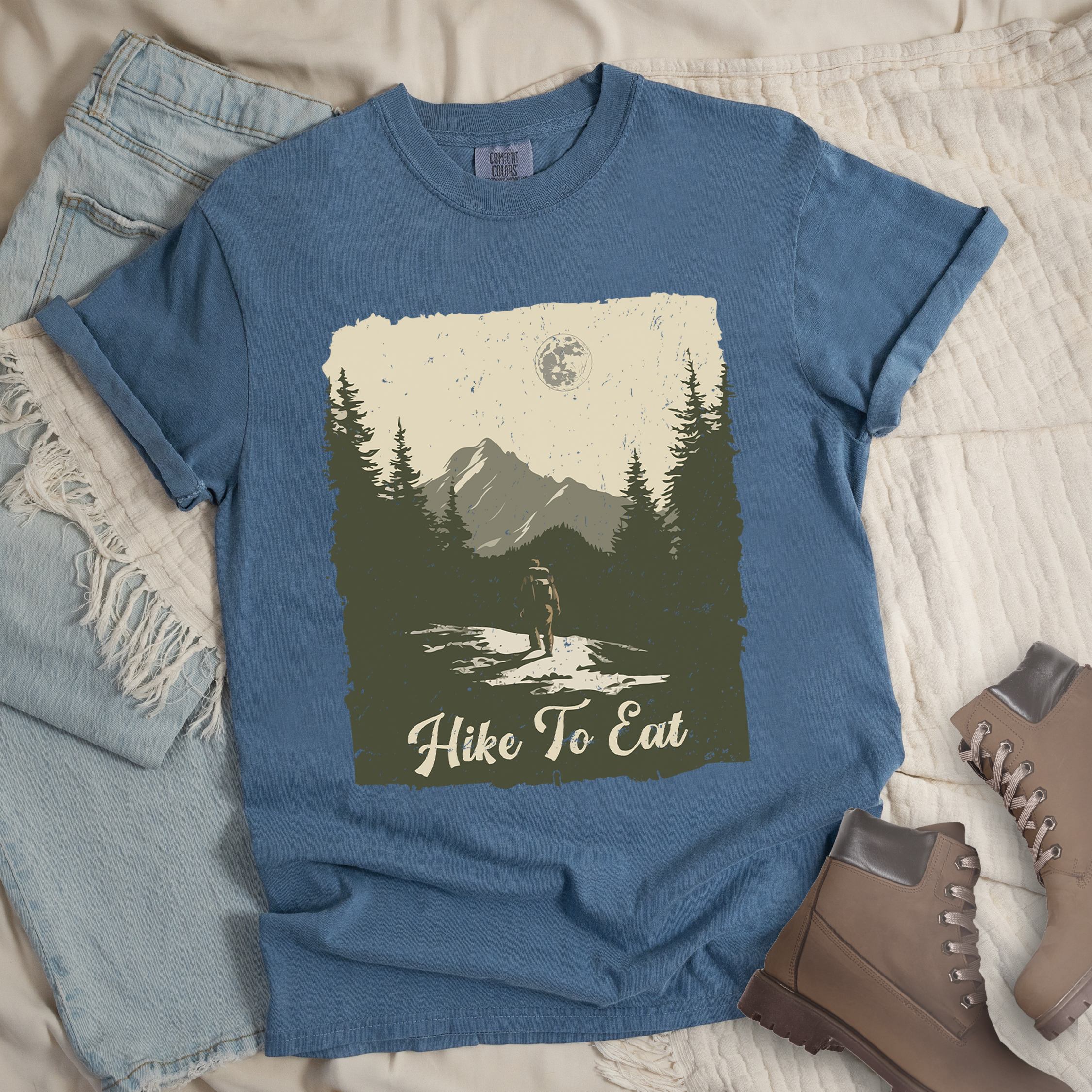 Dark blue shirt with Hiking Design featuring the phrase “Hike to Eat” and an illustration of a lone hiker walking toward mountains under the moonlight in a nature scene.