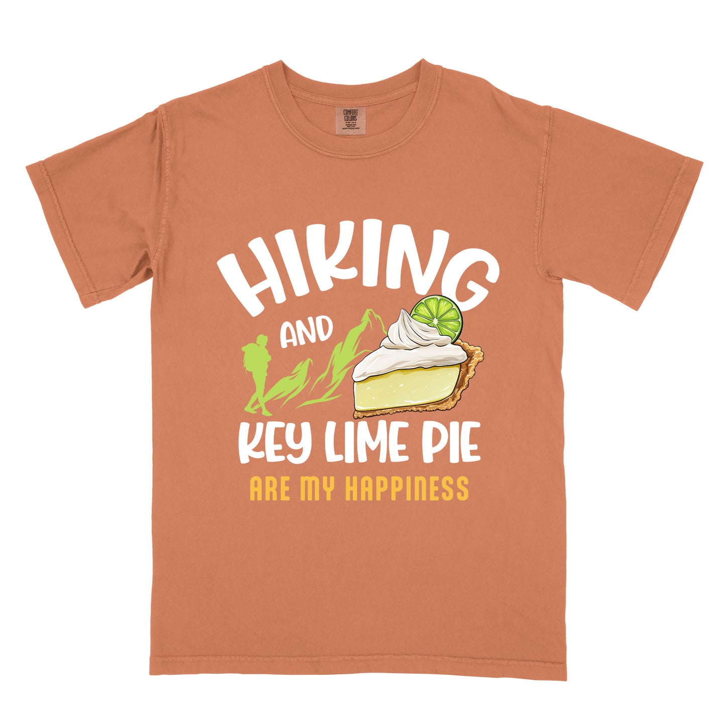 Yam (Brown) t-shirt with text "HIKING AND KEY LIME PIE ARE MY HAPPINESS". "HIKING" appears in white arched letters at the top, "AND" in small white text, "KEY LIME PIE" in large white text in the middle, and "ARE MY HAPPINESS" in gold/yellow at the bottom. The design includes green mountain silhouettes with a hiker silhouette and an illustration of a slice of key lime pie with whipped cream and lime garnish in between "AND" and "KEY LIME PIE." 