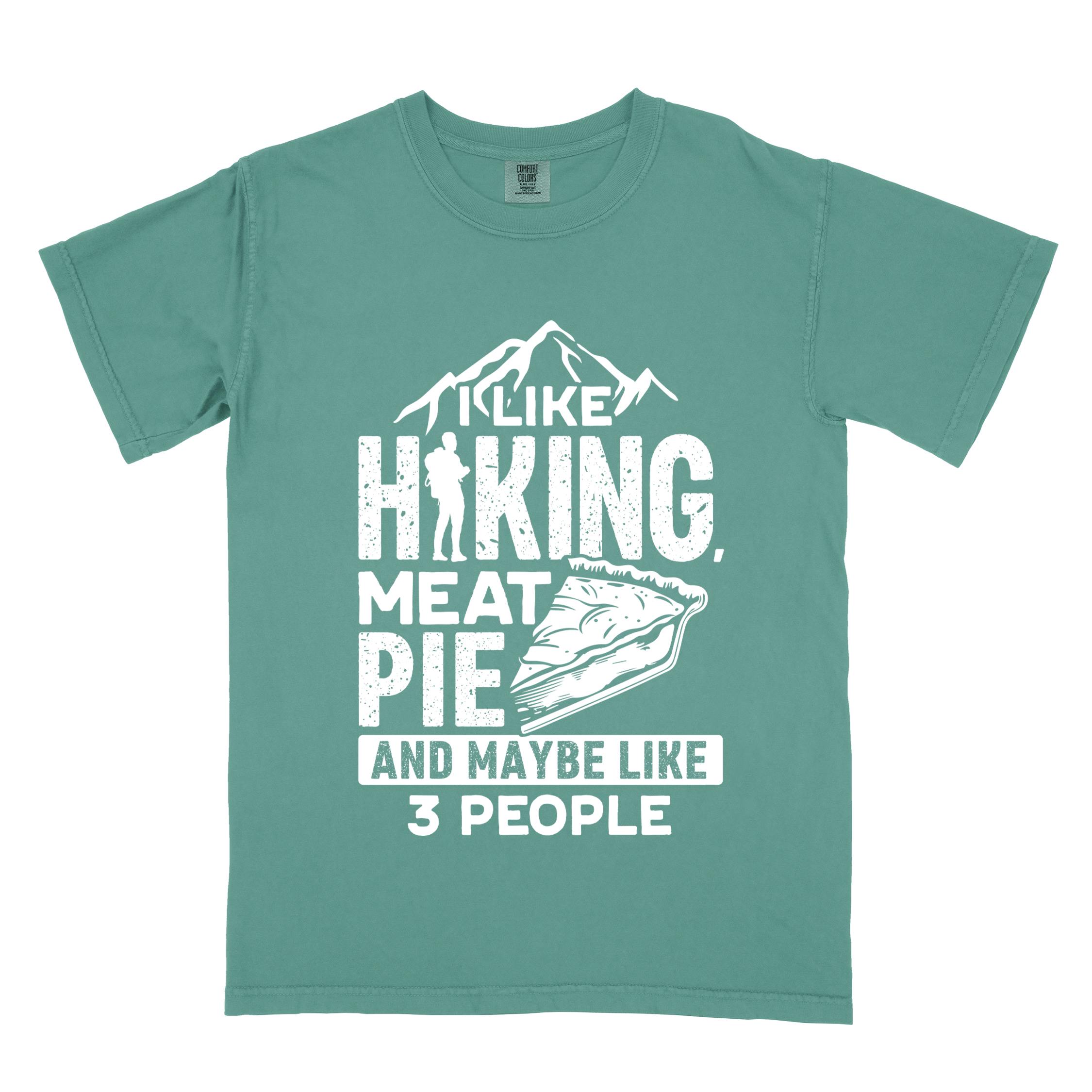 Light green "I like hiking, meat pie and maybe like 3 people" colored vintage tee with bold typography, mountains, birds, illustrated slice of meat pie, and backpacker for pie lovers.