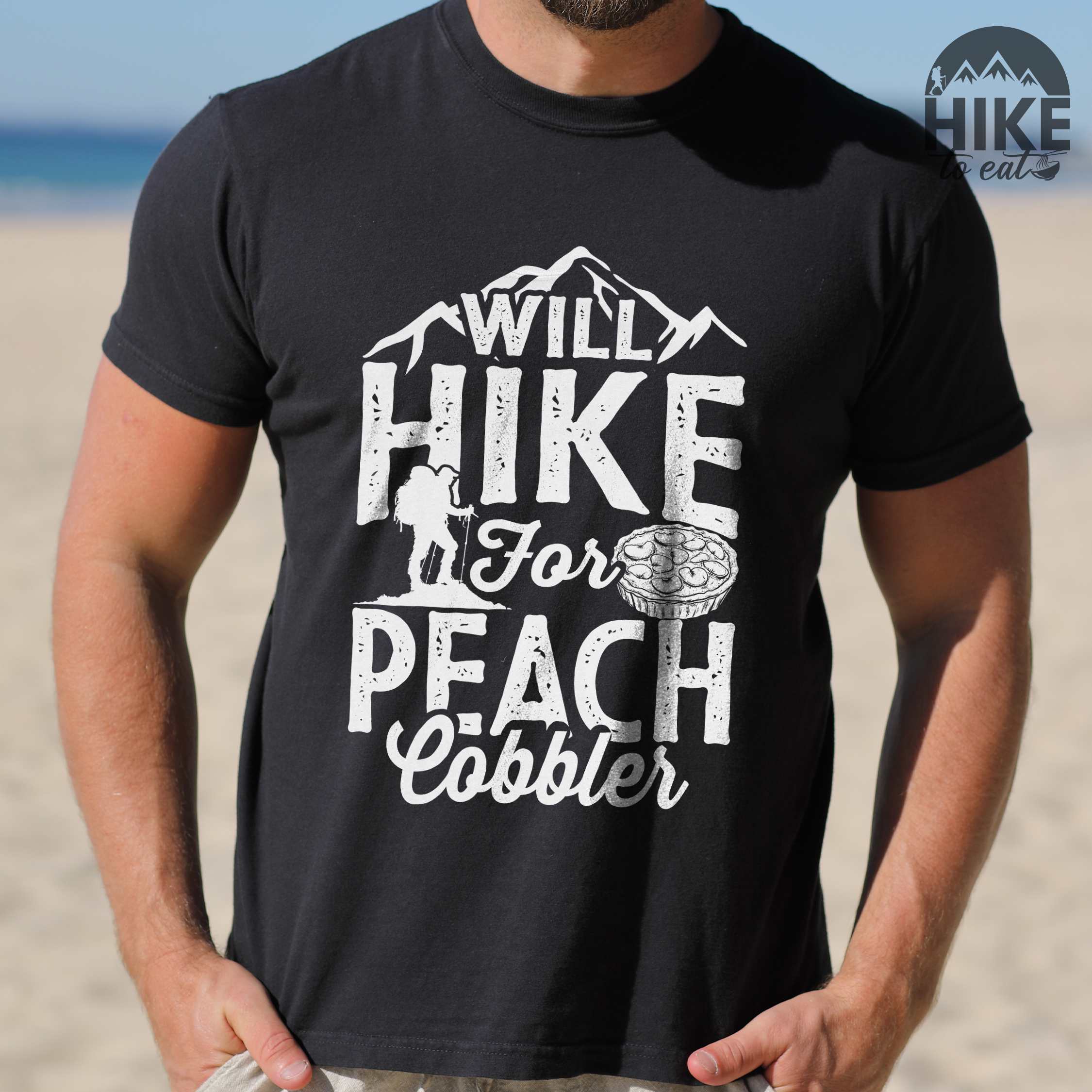 Man wearing black "Will hike for peach cobbler" colored vintage tee with bold typography, mountain, birds, illustrated peach cobbler, and backpacker looking for sweet treats.