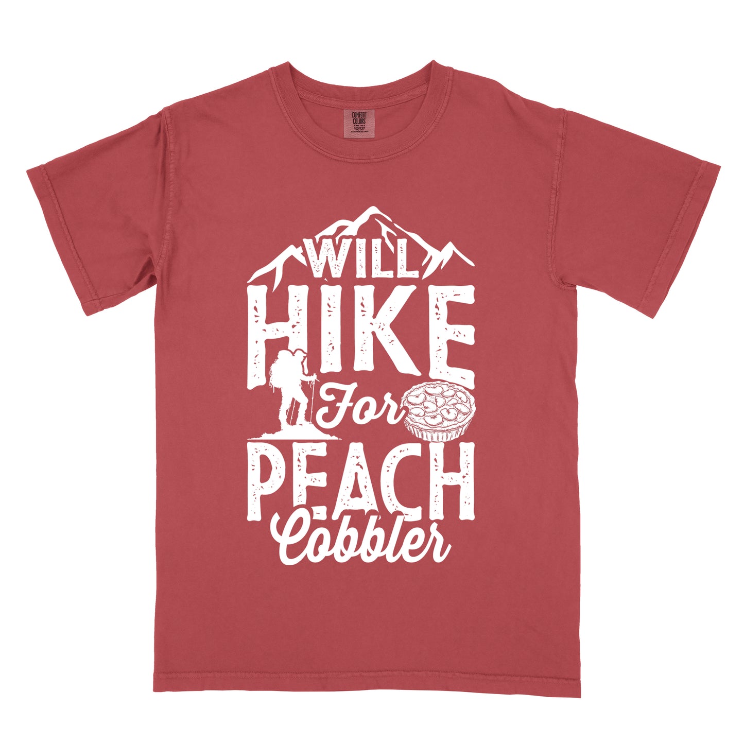 Crimson (Dark Pink) t-shirt with white text reading "WILL HIKE FOR PEACH COBBLER". "WILL HIKE" appears in large distressed letters at the top with mountain silhouettes, "For" in white script across the middle, and "PEACH COBBLER" in large distressed letters at the bottom. The design includes a small hiker figure with backpack on the left and an illustration of a peach cobbler pie. The design humorously connects hiking activity with dessert motivation.