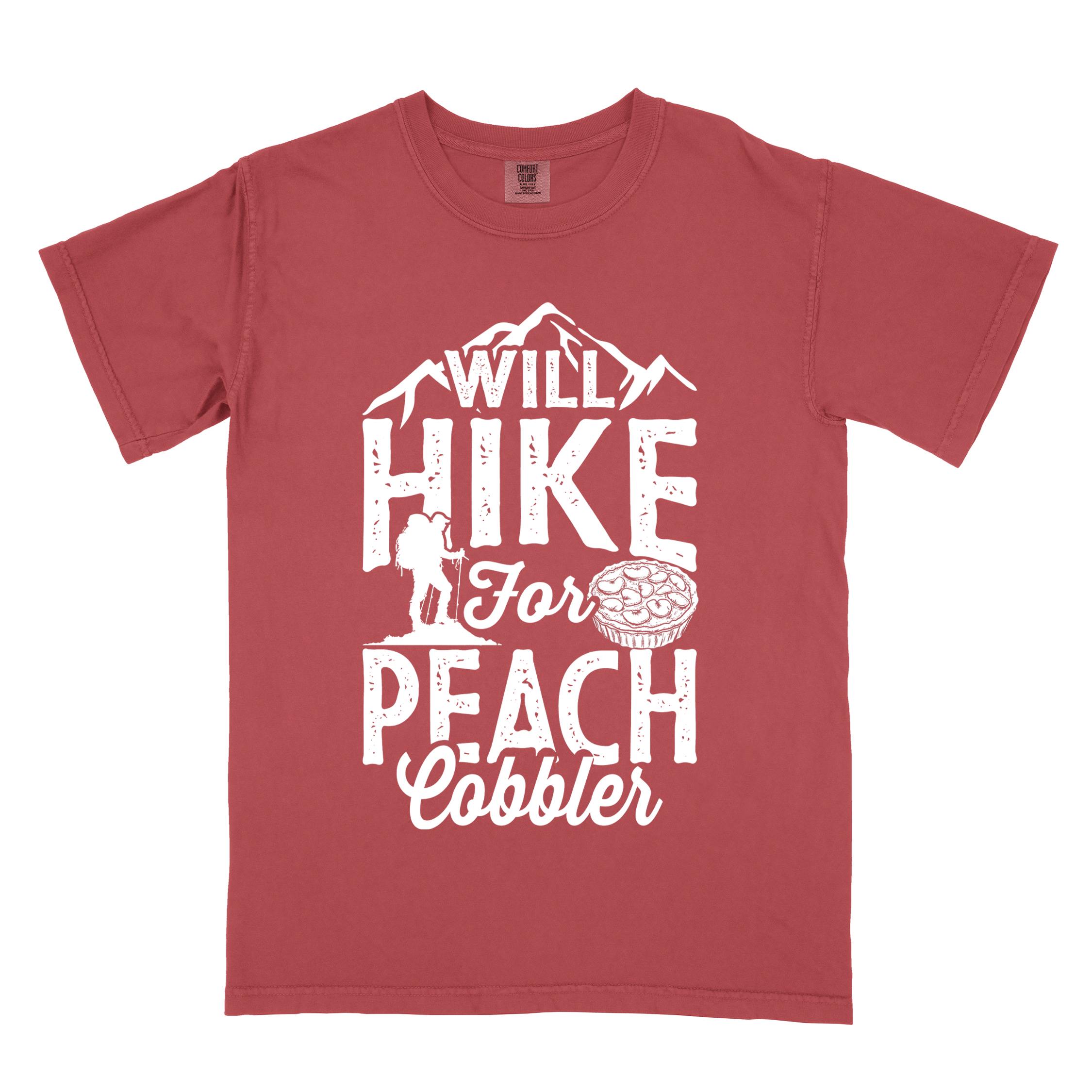 Crimson "Will hike for peach cobbler" colored vintage tee with bold typography, mountain, birds, illustrated peach cobbler, and backpacker looking for sweet treats.