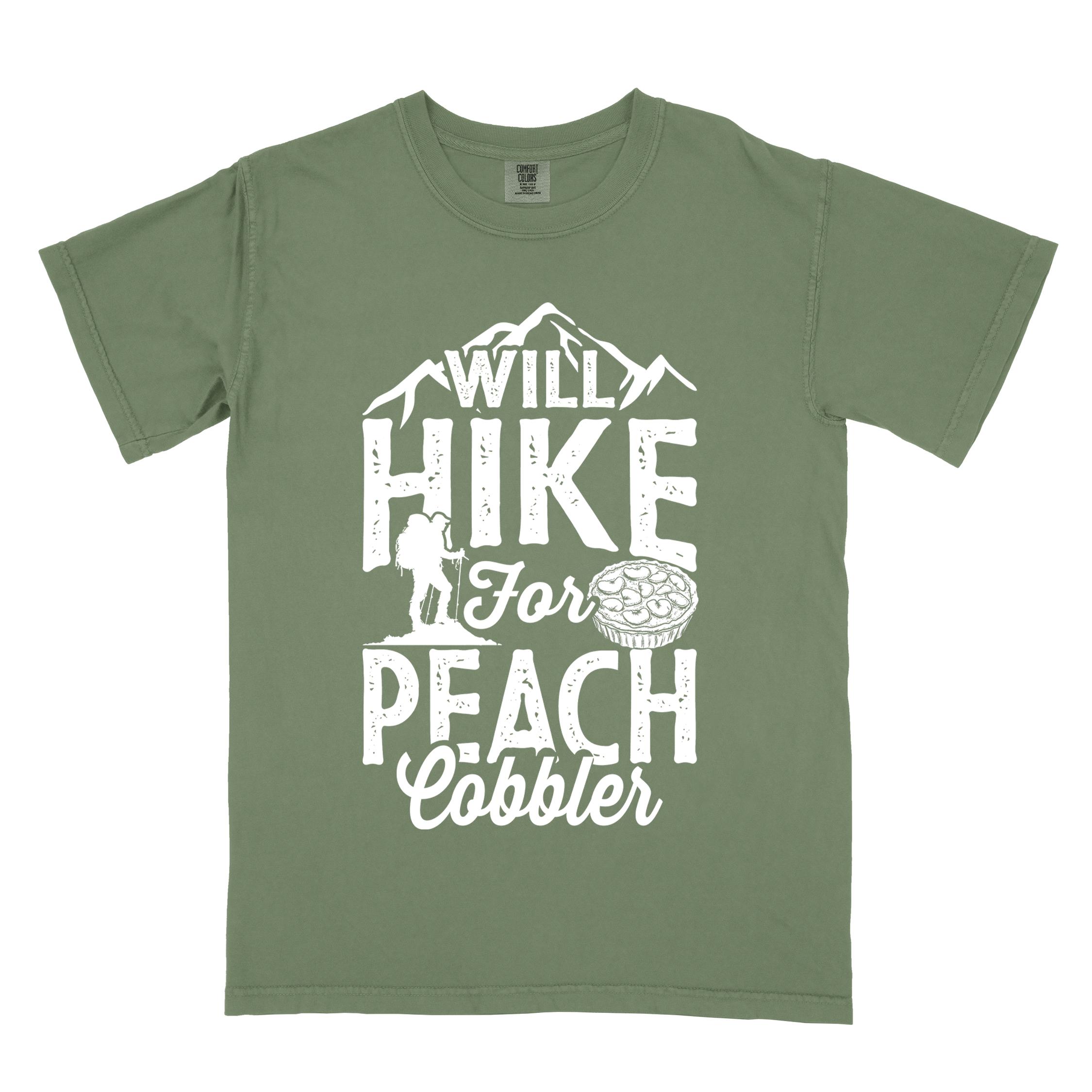 Moss "Will hike for peach cobbler" colored vintage tee with bold typography, mountain, birds, illustrated peach cobbler, and backpacker looking for sweet treats.