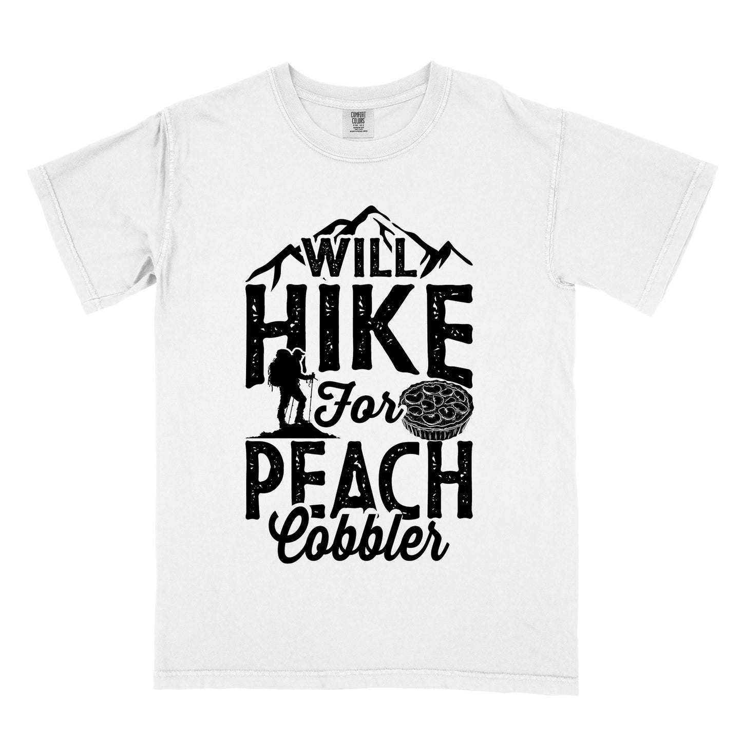 White t-shirt with black text reading "WILL HIKE FOR PEACH COBBLER". "WILL HIKE" appears in large distressed letters at the top with mountain silhouettes, "For" in black script across the middle, and "PEACH COBBLER" in large distressed letters at the bottom. The design includes a small hiker figure with backpack on the left and an illustration of a peach cobbler pie. The design humorously connects hiking activity with dessert motivation.