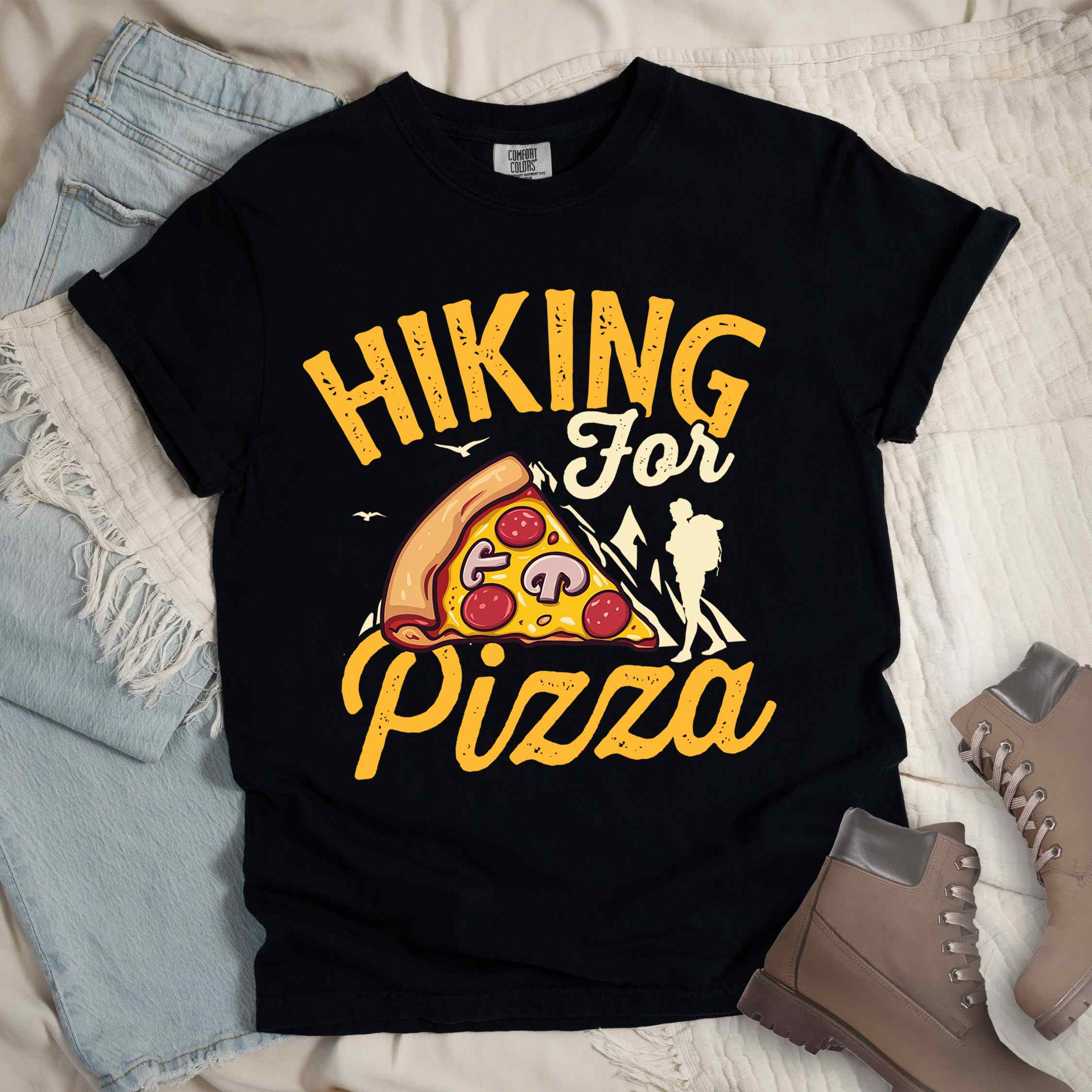 Black "Hiking for Pizza" colored vintage tee with bold typography, birds, mountains, illustrated pizza slice, and backpacker for pizza lovers.