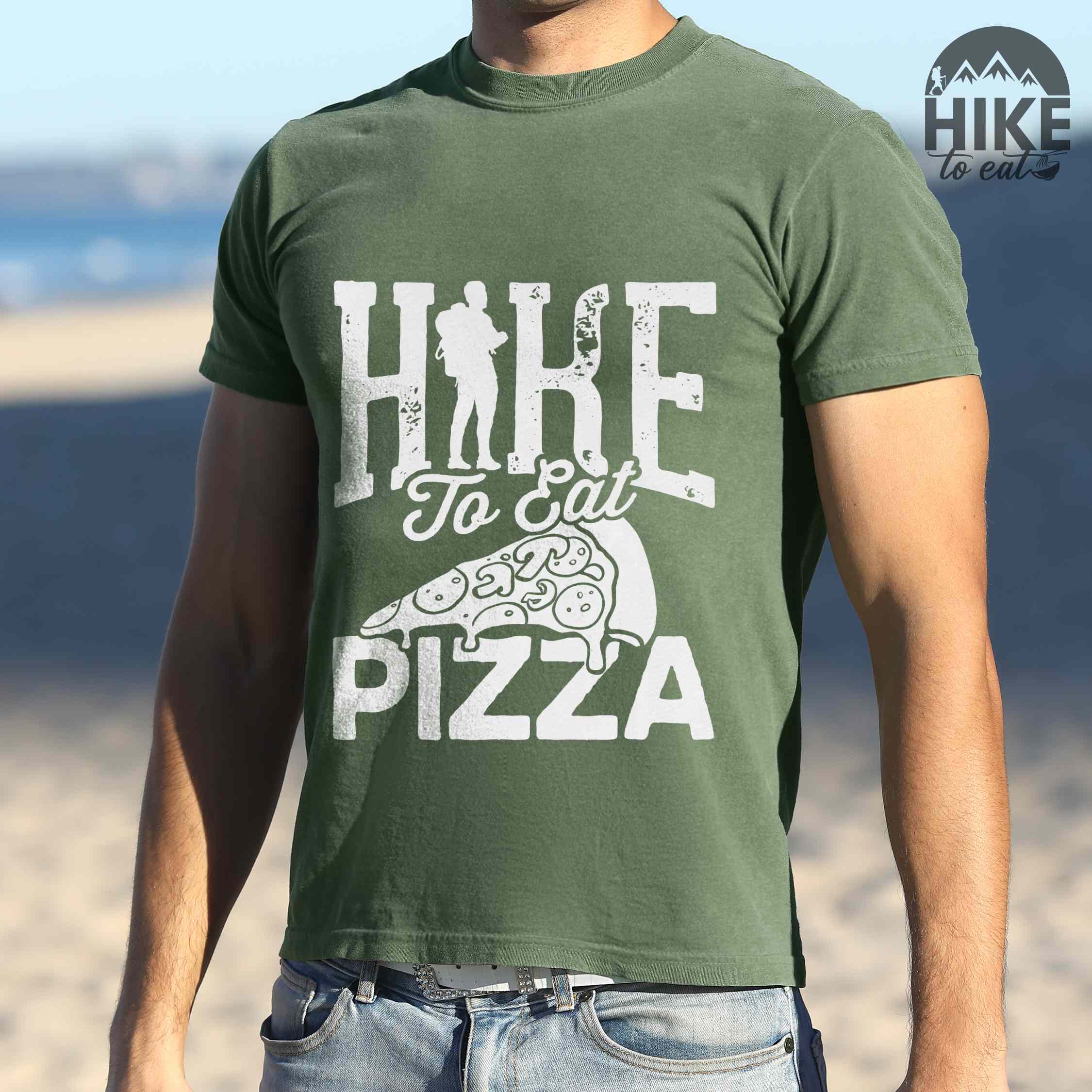 Man wearing moss "Hike to eat Pizza" colored vintage tee with bold typography, birds, mountains, illustrated pizza slice, and backpacker for pizza lover.