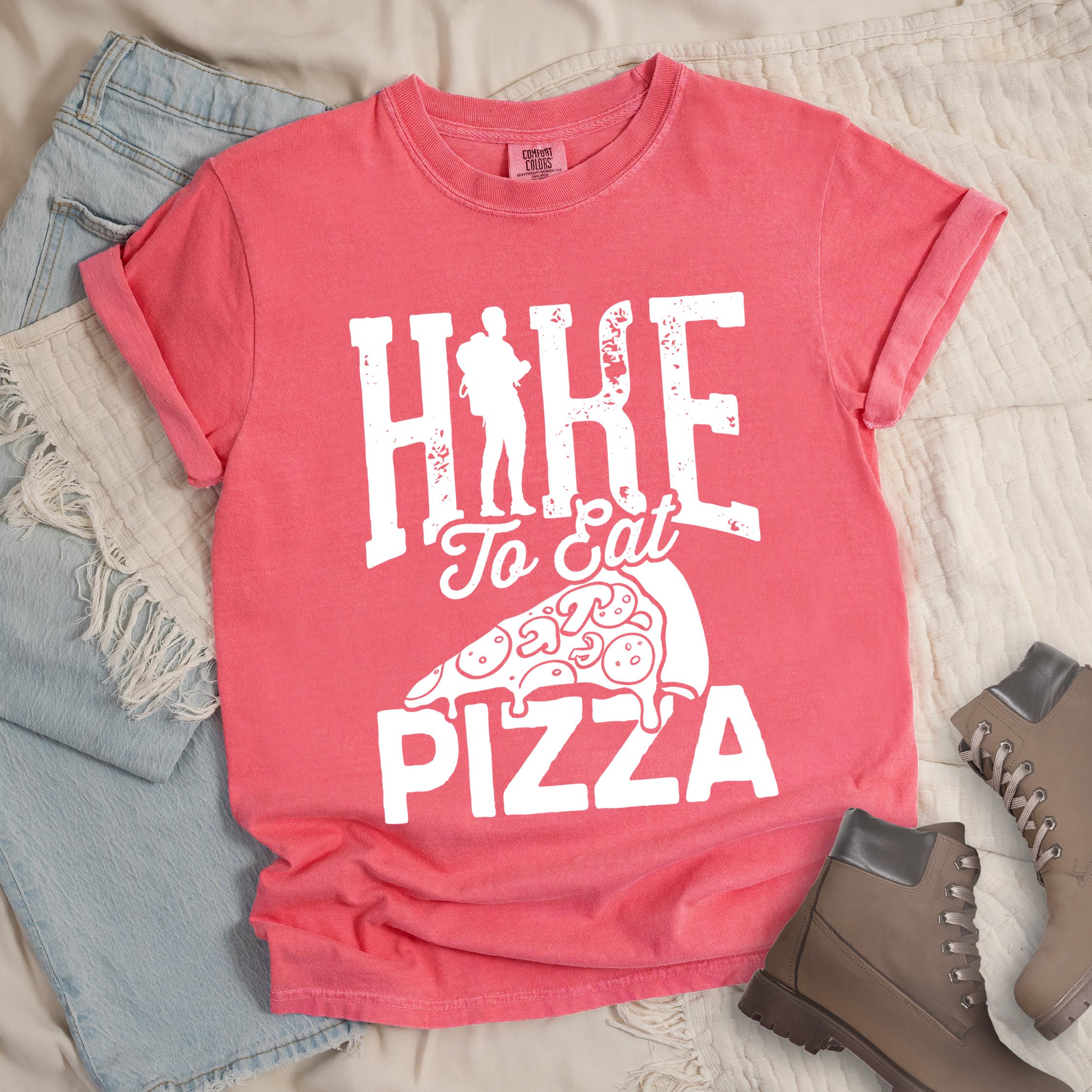 Pink shirt with Hiking Design featuring the phrase “Hike to Eat Pizza” with a bold hiker silhouette and an illustration of a large pizza slice.