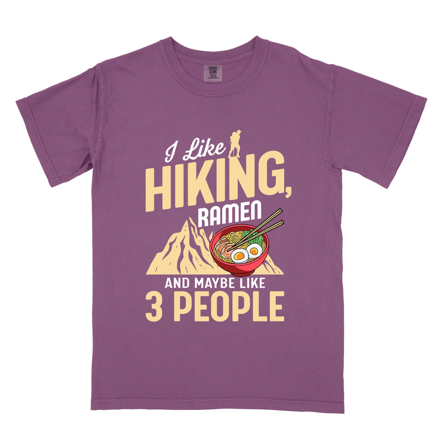 Berry (Dark Violet) t-shirt with mixed text reading "I Like HIKING, RAMEN AND MAYBE LIKE 3 PEOPLE". "I Like" in white script at top with small gold hiker silhouette, "HIKING," in large gold letters, "RAMEN" in white, and "AND MAYBE LIKE 3 PEOPLE" in white and gold. Features a colorful illustration of a red ramen bowl with eggs, noodles and chopsticks, positioned above a gold mountain silhouette.