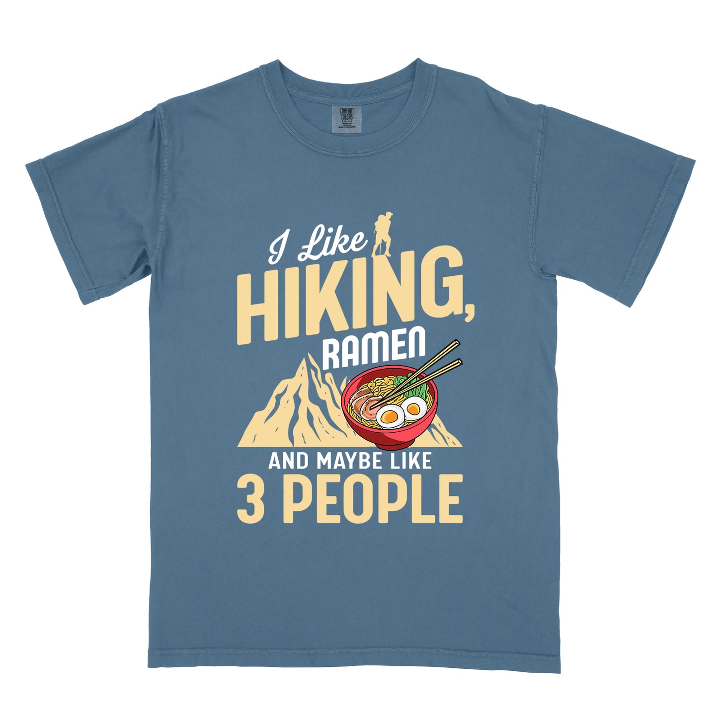 Blue Jean (Denim Blue) t-shirt with mixed text reading "I Like HIKING, RAMEN AND MAYBE LIKE 3 PEOPLE". "I Like" in white script at top with small gold hiker silhouette, "HIKING," in large gold letters, "RAMEN" in white, and "AND MAYBE LIKE 3 PEOPLE" in white and gold. Features a colorful illustration of a red ramen bowl with eggs, noodles and chopsticks, positioned above a gold mountain silhouette.