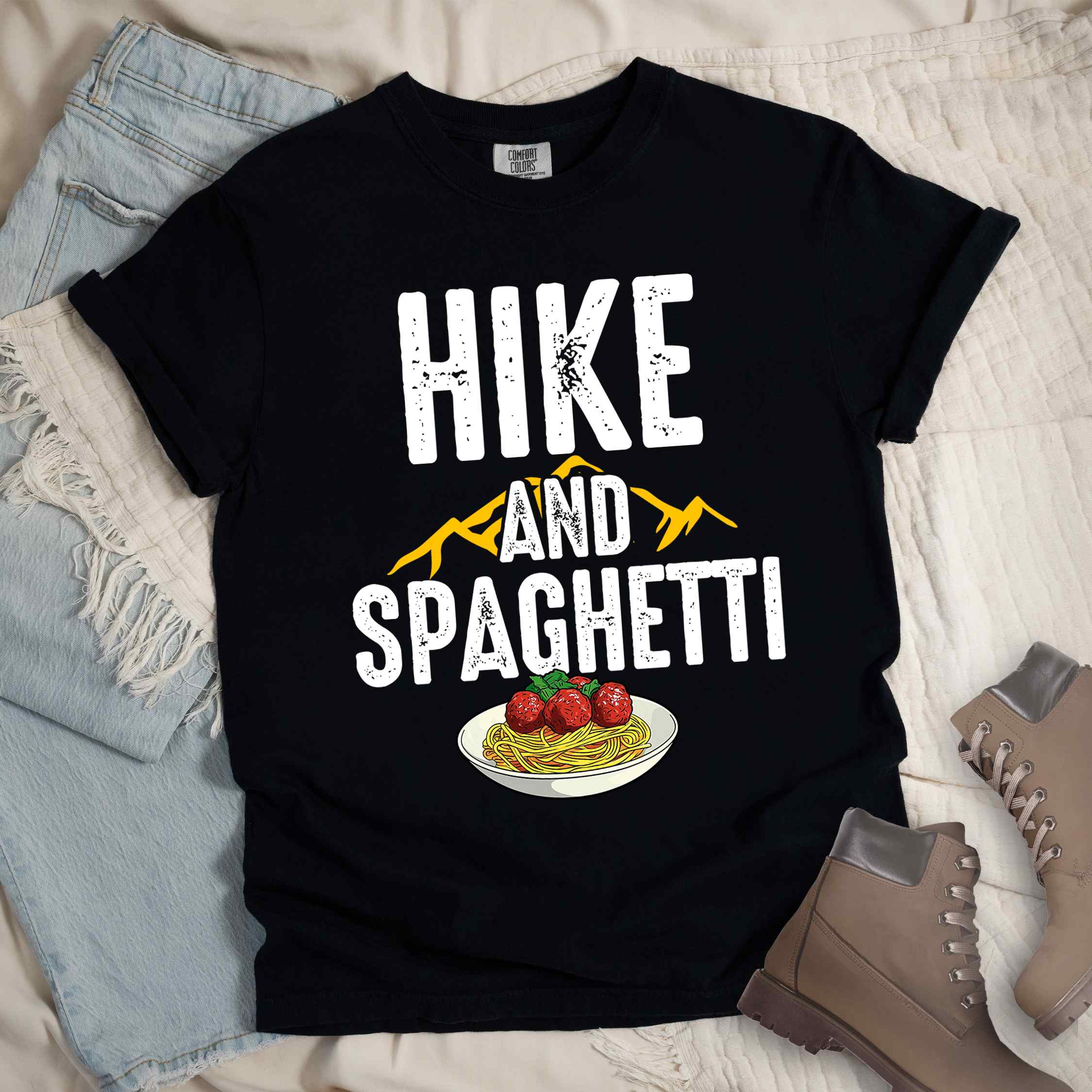 Black "Hike and Spaghetti" colored vintage tee with bold typography, birds, mountains, illustrated plate of spaghetti and meatballs, and backpacker for pasta lovers.