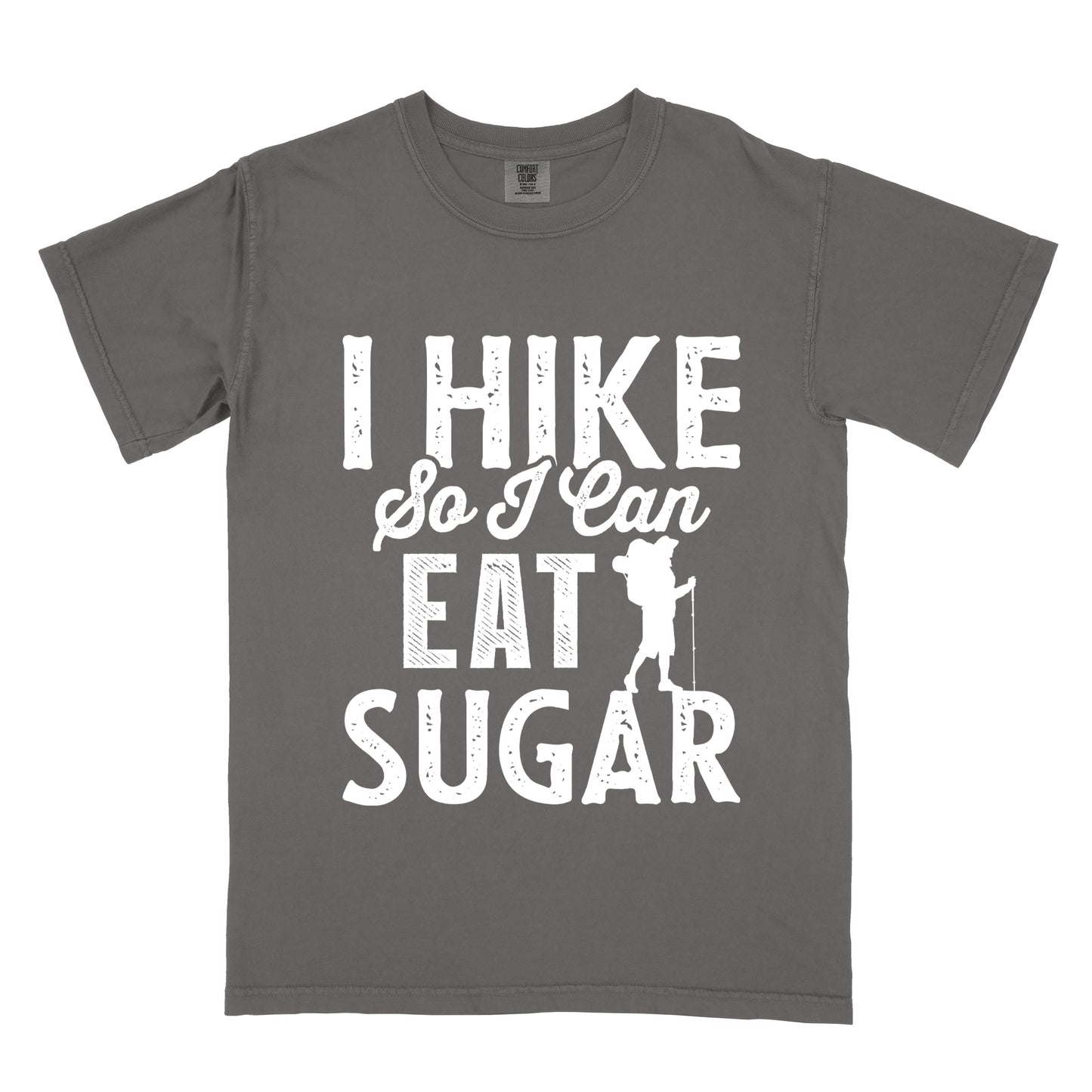 Pepper (Dark Gray) t-shirt with white distressed text reading "I HIKE So I Can EAT SUGAR". "I HIKE" appears in large block letters at the top, "So I Can" in script in the middle, and "EAT SUGAR" in block letters at the bottom. A small silhouette of a hiker with backpack and walking stick is positioned next to the word "EAT" and above "SUGAR".