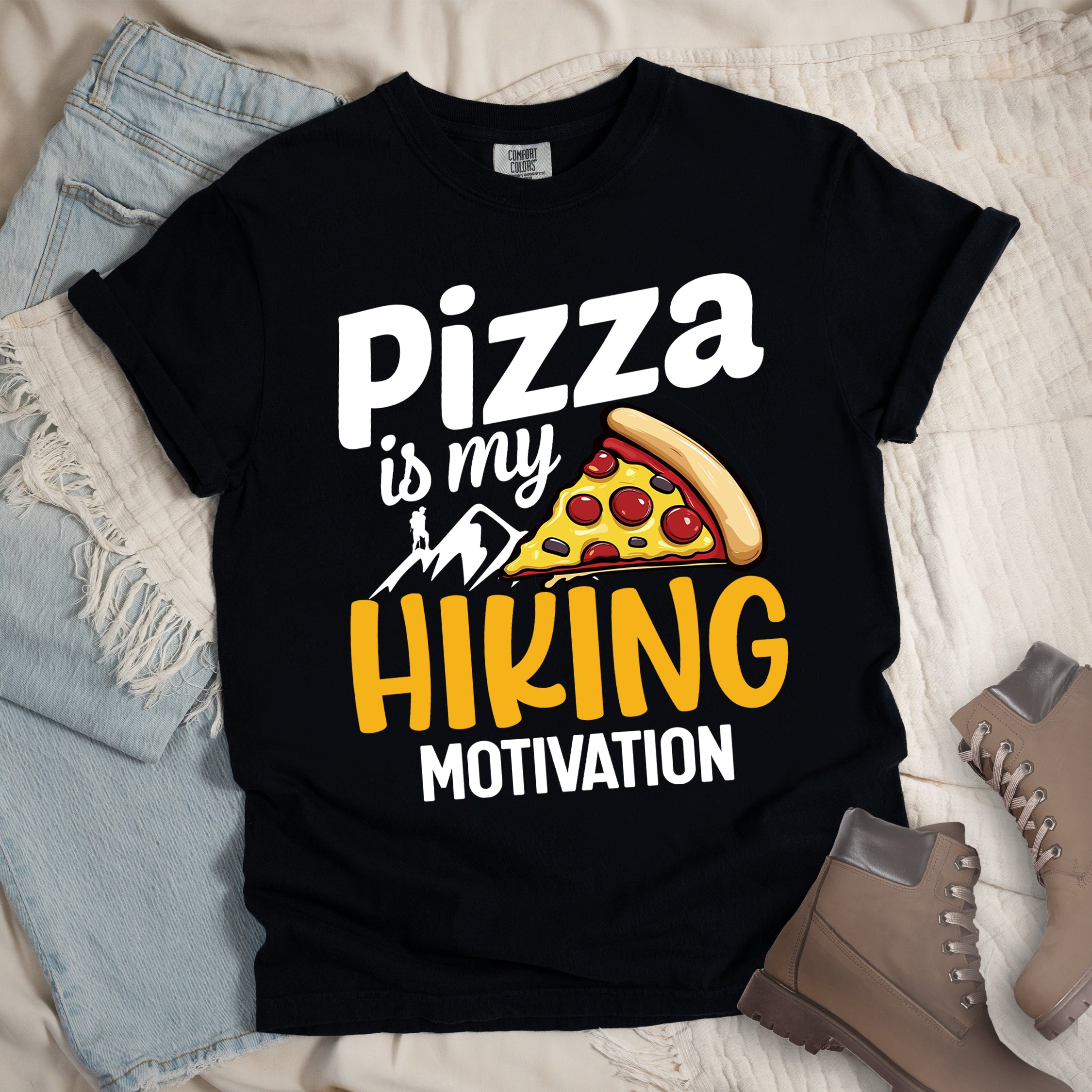 Black t-shirt with white and yellow text reading "Pizza is my HIKING MOTIVATION". "Pizza" appears in large white letters at the top, "is my" in smaller white script, "HIKING" in yellow at the bottom, and "MOTIVATION" in white. Features a colorful pizza slice with pepperoni toppings, white mountain silhouettes with a small hiker figure on a peak. The design humorously connects pizza as the incentive for hiking activities. 
