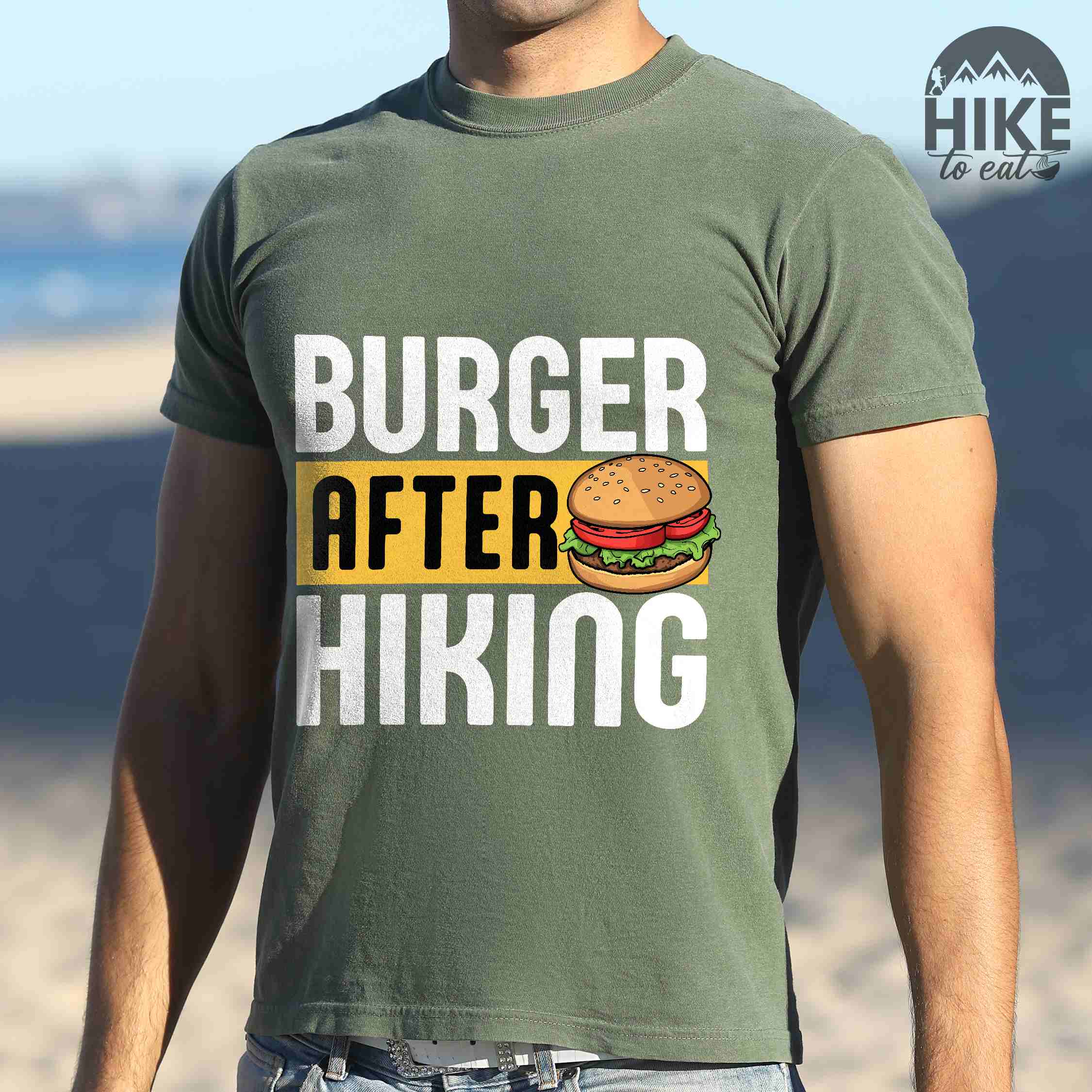 Man wearing Moss "Burger after Hiking" colored vintage tee with bold typography, birds, mountains, illustrated juicy hamburger, and backpacker for burger enthusiasts.