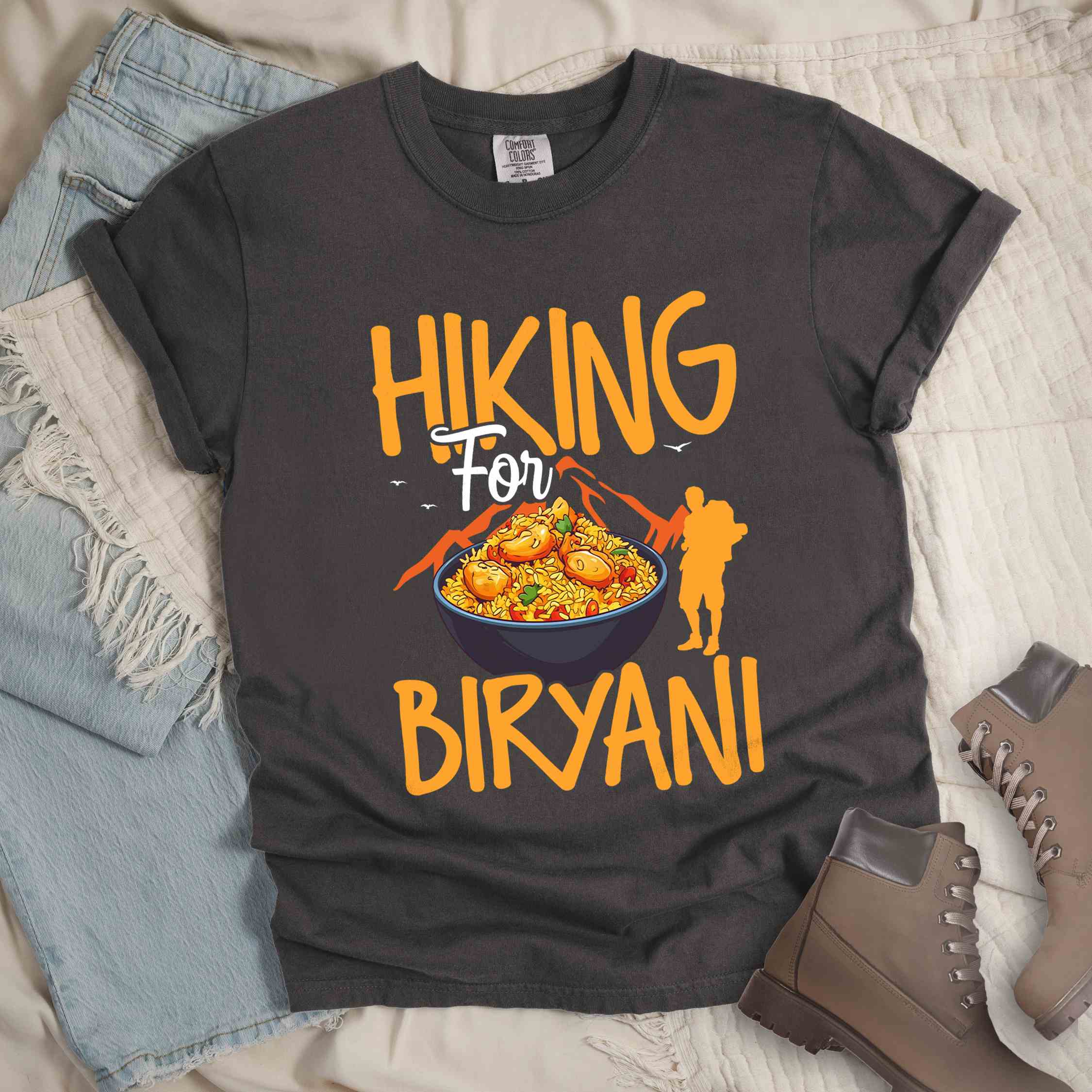 Pepper "Hiking for Biryani" colored vintage tee with bold typography, birds, mountains, illustrated bowl of biryani rice, and backpacker for rice lovers.