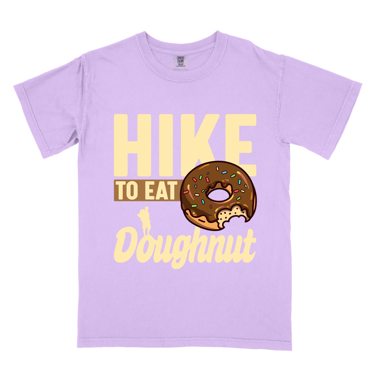 Orchid (Light Violet) t-shirt with cream and tan text reading "HIKE TO EAT Doughnut". "HIKE" appears in large cream letters at the top, "TO EAT" on a tan rectangular background in the middle, and "Doughnut" in cream script at the bottom. Features a chocolate frosted doughnut with colorful sprinkles and a bite taken out of it on the right side, and a small cream silhouette of a hiker on the left. 