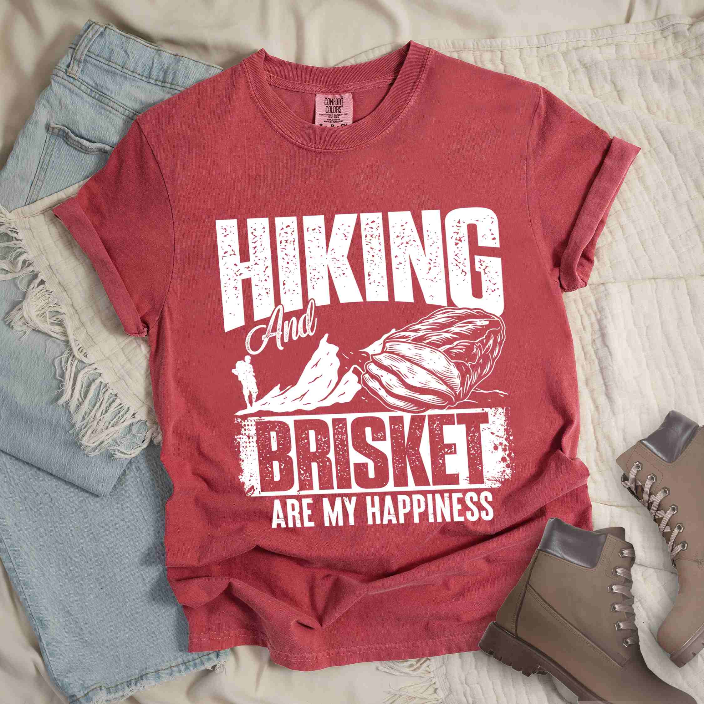 Crimson "hiking and brisket are my happiness" colored vintage tee with bold typography, birds, mountains, illustrated bbq beef brisket, and backpacker for bbq lovers.