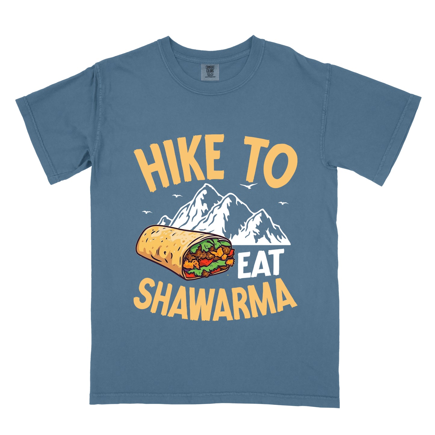 Blue Jean (Denim Blue) t-shirt with golden yellow and white text reading "HIKE TO EAT SHAWARMA". "HIKE TO" appears in golden yellow letters at the top, "EAT" in white in the middle, and "SHAWARMA" in golden yellow at the bottom. Features a detailed illustration of a shawarma wrap with visible meat and vegetables, white mountain silhouettes with small bird silhouettes in the background. 