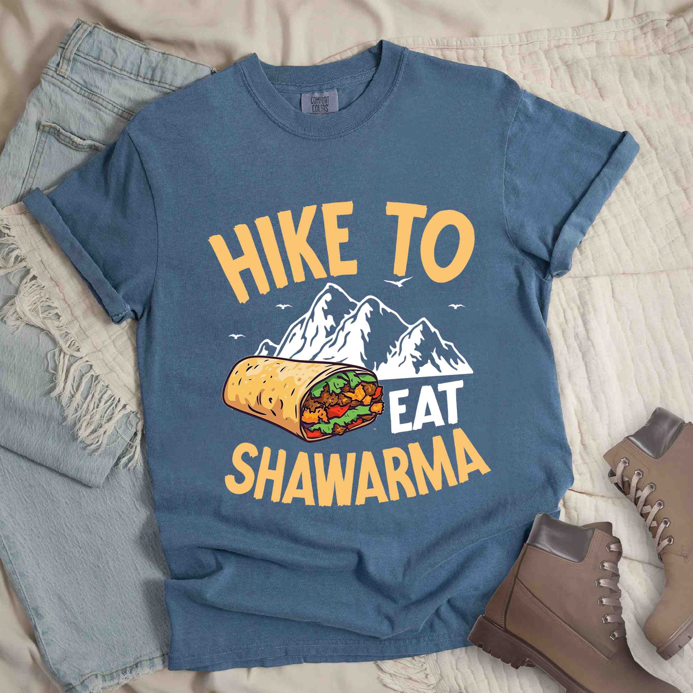 Blue jean "Hike to Eat Shawarma" colored vintage tee with bold typography, mountains, birds, and illustrated shawarma, and backpackers for shawarma lovers.