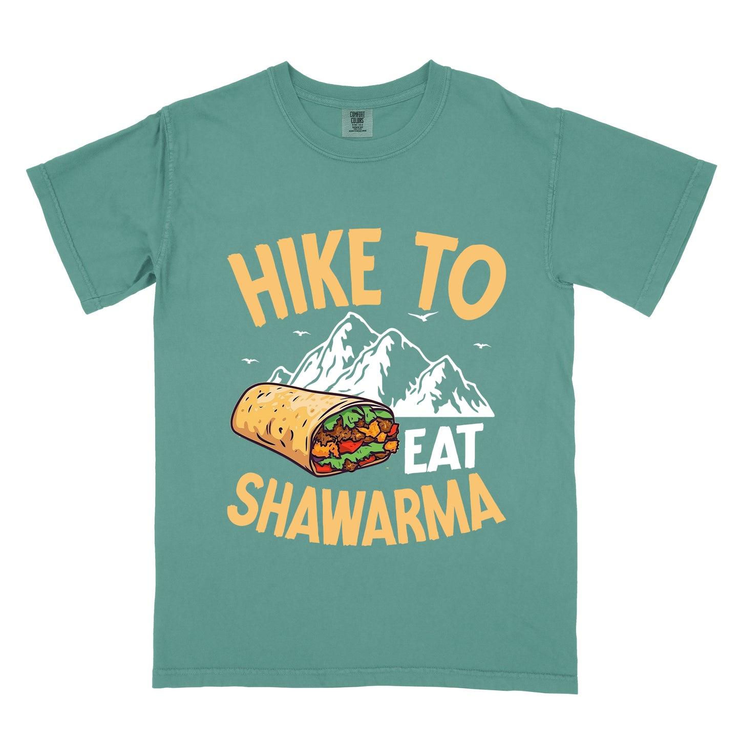 Light Green t-shirt with golden yellow and white text reading "HIKE TO EAT SHAWARMA". "HIKE TO" appears in golden yellow letters at the top, "EAT" in white in the middle, and "SHAWARMA" in golden yellow at the bottom. Features a detailed illustration of a shawarma wrap with visible meat and vegetables, white mountain silhouettes with small bird silhouettes in the background. 