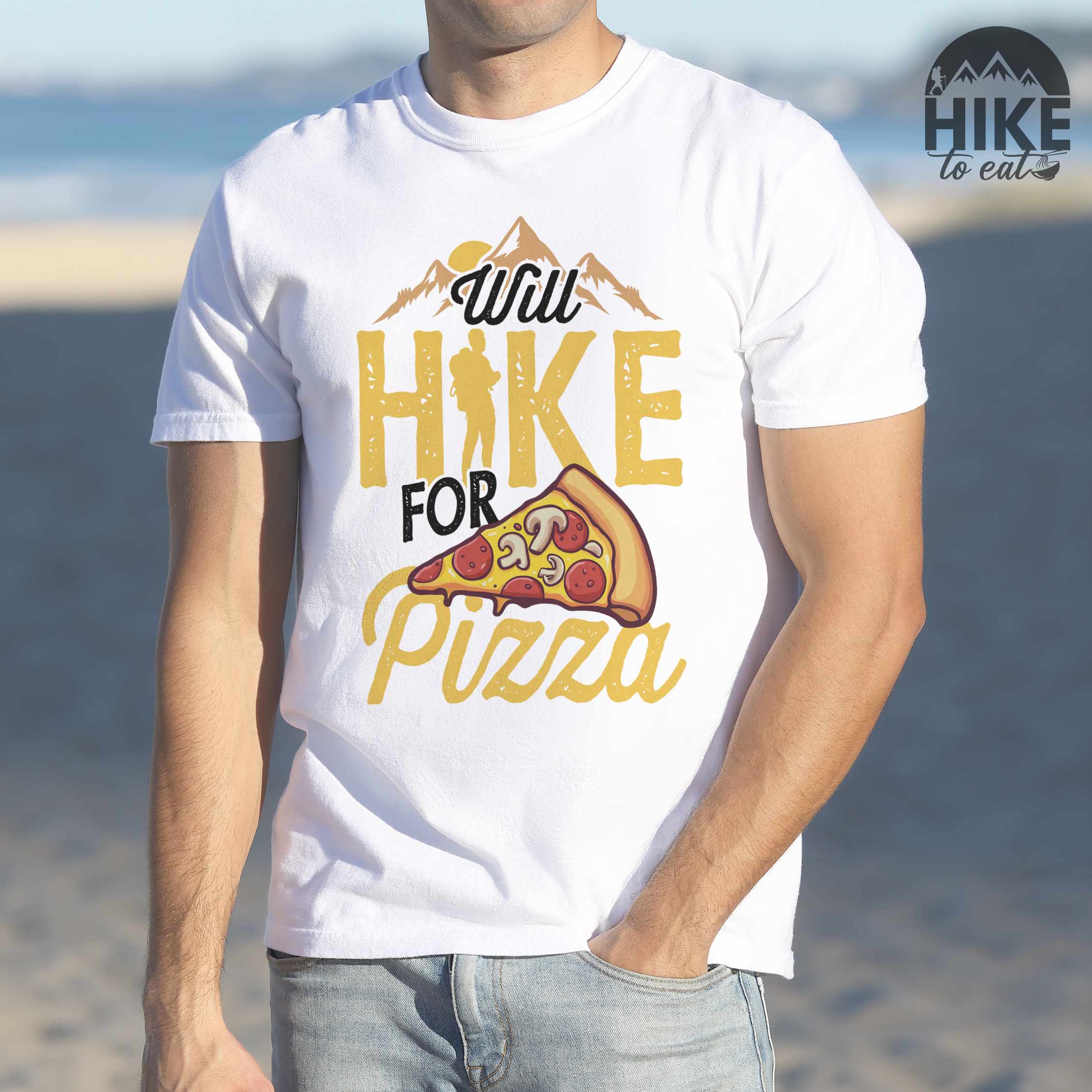 Man wearing white colored vintage tee featuring Hiking design of mountains with a sunrise behind and a slice of pizza in front of the phrase 'Will Hike for Pizza'.