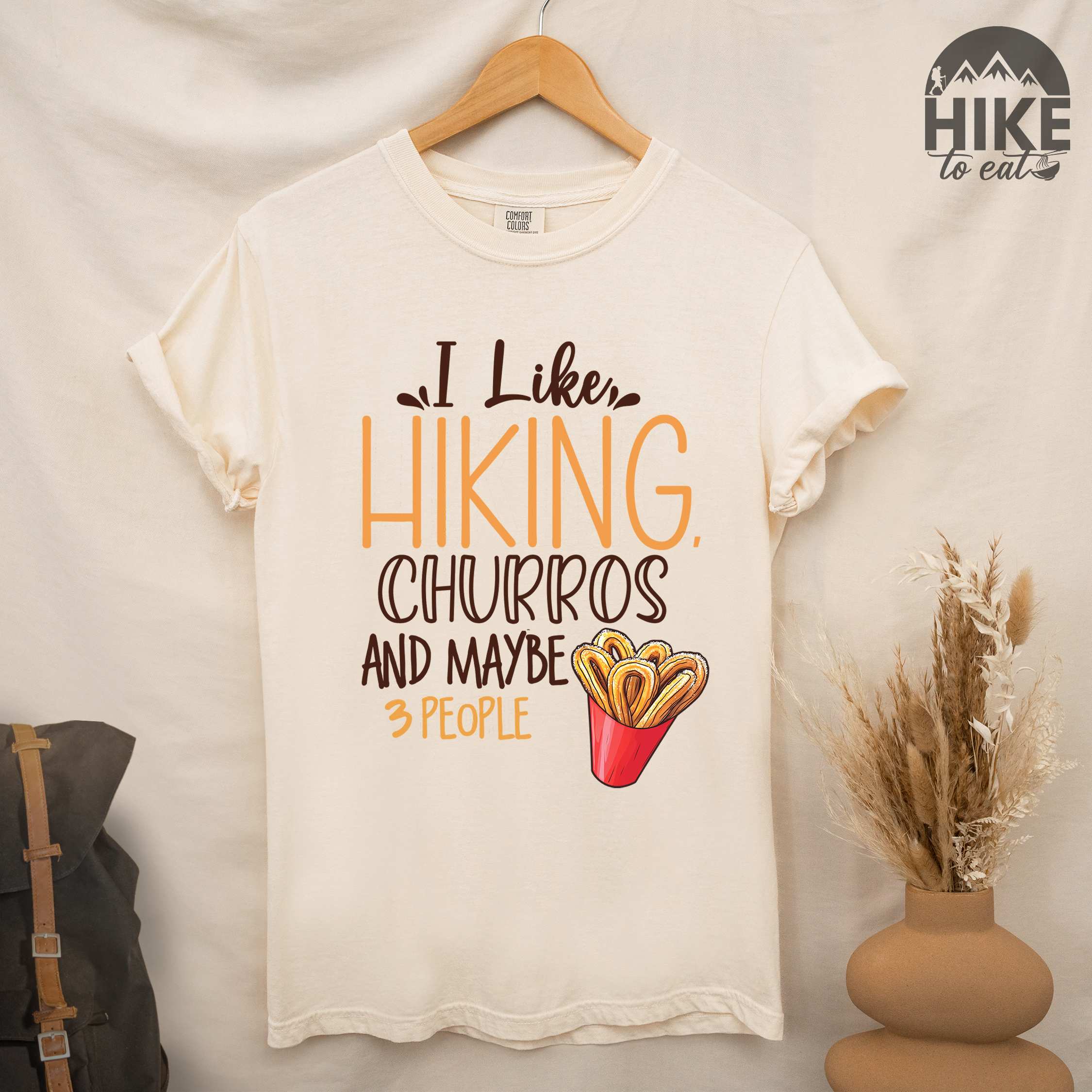 Hanging ivory "I like hiking, churros and maybe three people " colored vintage tee with bold typography, mountains, illustrated a serving of Churros, and backpackers with a sweet tooth.