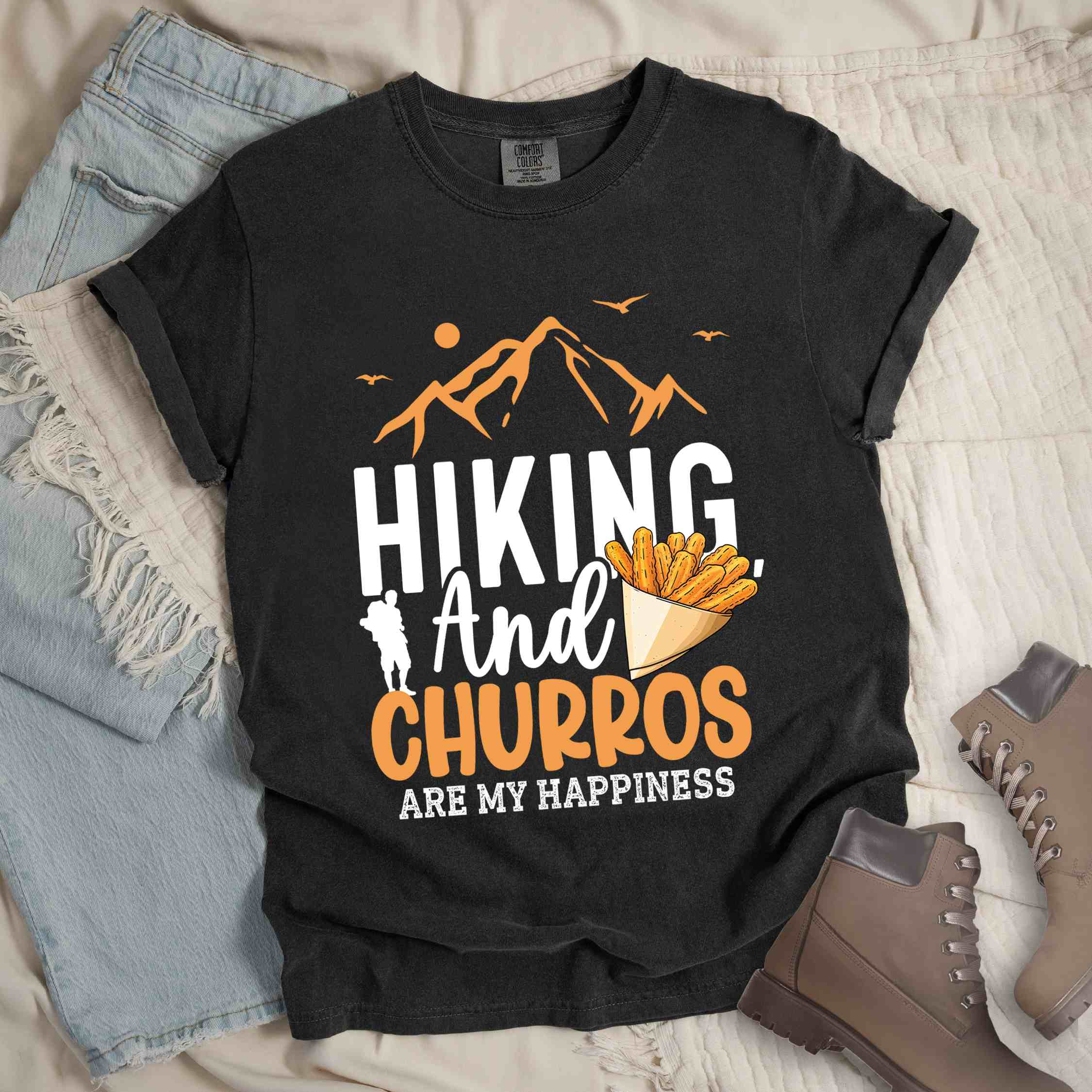 Graphite "hiking and churros are my happiness " colored vintage tee with bold typography, mountains, birds, illustrated a serving of Churros, and backpackers with a sweet tooth.
