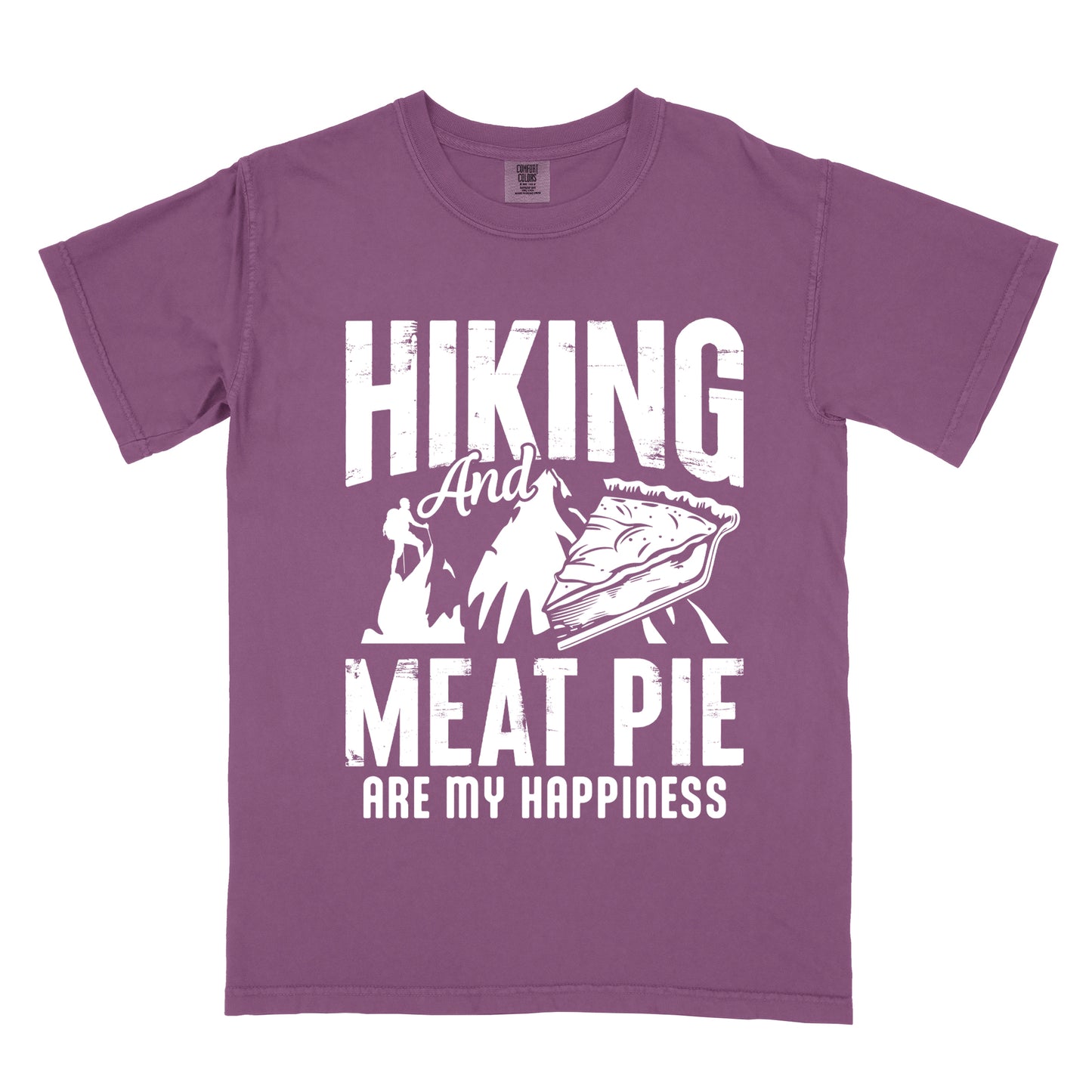 A Berry (Dark Violet) t-shirt featuring white distressed text reading "HIKING And MEAT PIE ARE MY HAPPINESS." Between the words "HIKING" and "MEAT PIE" is a graphic showing a mountain silhouette with a tiny hiker climbing it, alongside an illustration of a slice of meat pie. The design uses only white graphics and text on the Berry (Dark Violet) shirt background in a rugged, vintage style.