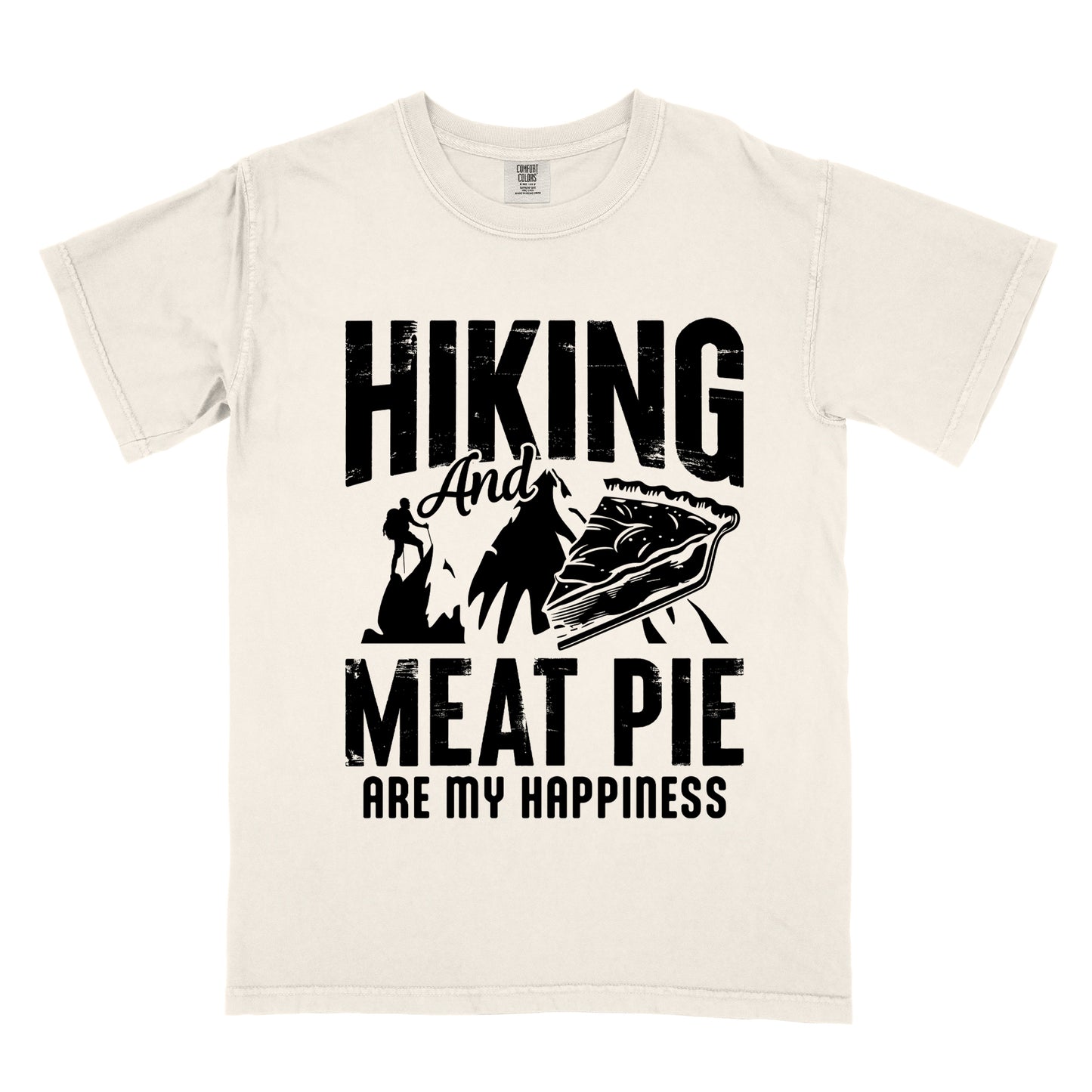 An Ivory (Cream White) t-shirt featuring black distressed text reading "HIKING And MEAT PIE ARE MY HAPPINESS." Between the words "HIKING" and "MEAT PIE" is a graphic showing a mountain silhouette with a tiny hiker climbing it, alongside an illustration of a slice of meat pie. The design uses only black graphics and text on the Ivory (Cream White) shirt background in a rugged, vintage style.