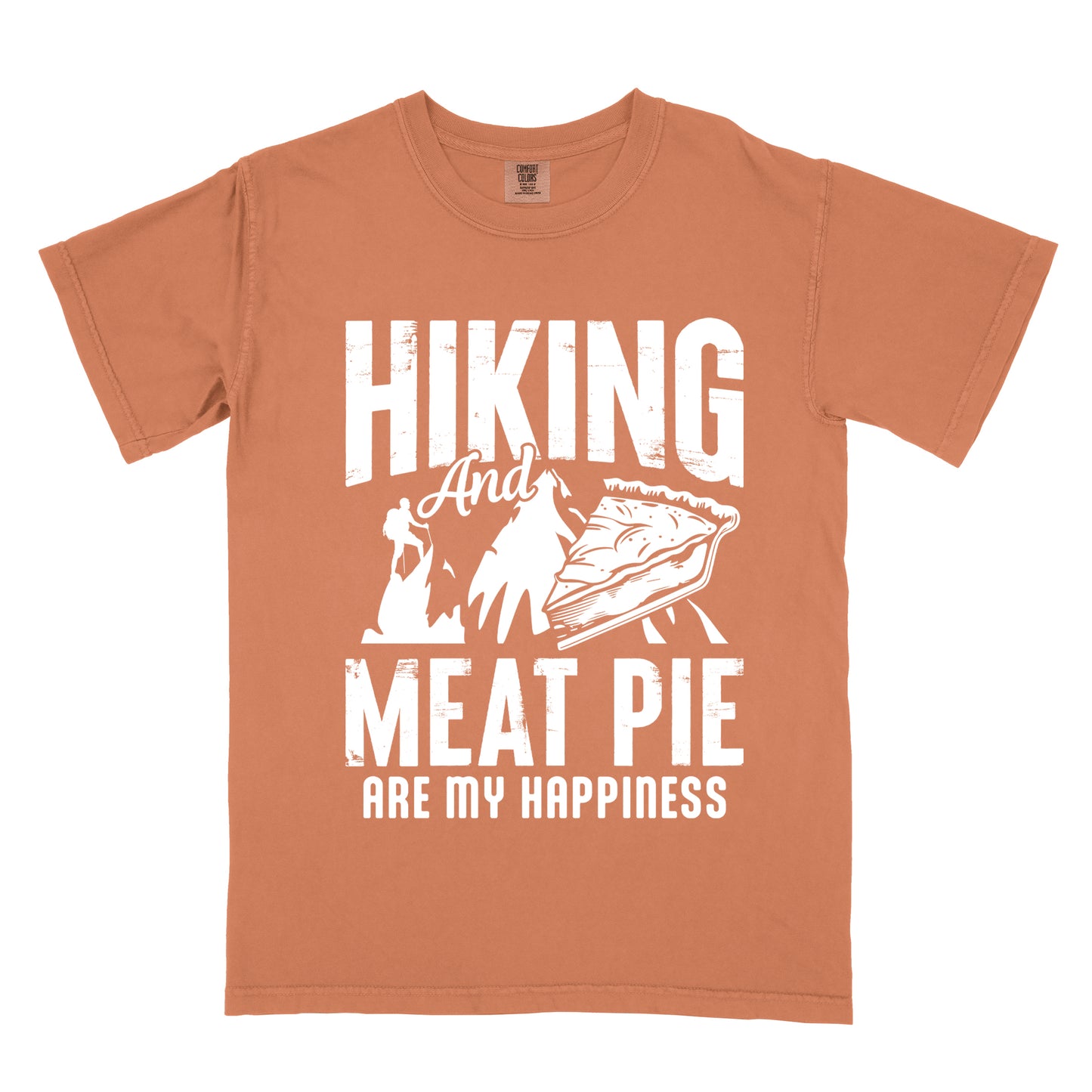 A Yam (Brown) t-shirt featuring white distressed text reading "HIKING And MEAT PIE ARE MY HAPPINESS." Between the words "HIKING" and "MEAT PIE" is a graphic showing a mountain silhouette with a tiny hiker climbing it, alongside an illustration of a slice of meat pie. The design uses only white graphics and text on the Yam (Brown) shirt background in a rugged, vintage style.