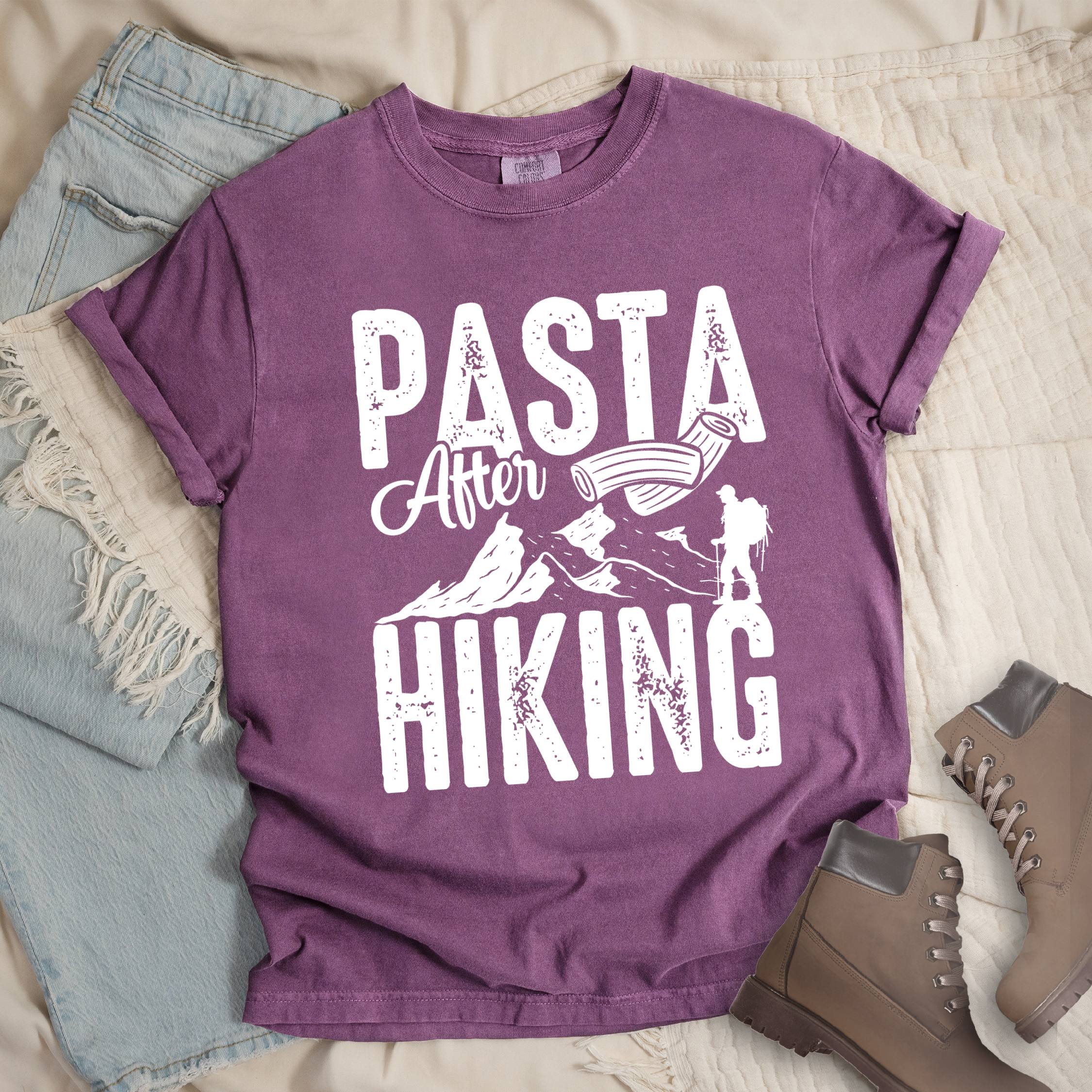 Dark pink shirt with the phrase “Pasta After Hiking.” Includes a hiker silhouette, mountain outline, and pasta noodle illustration.