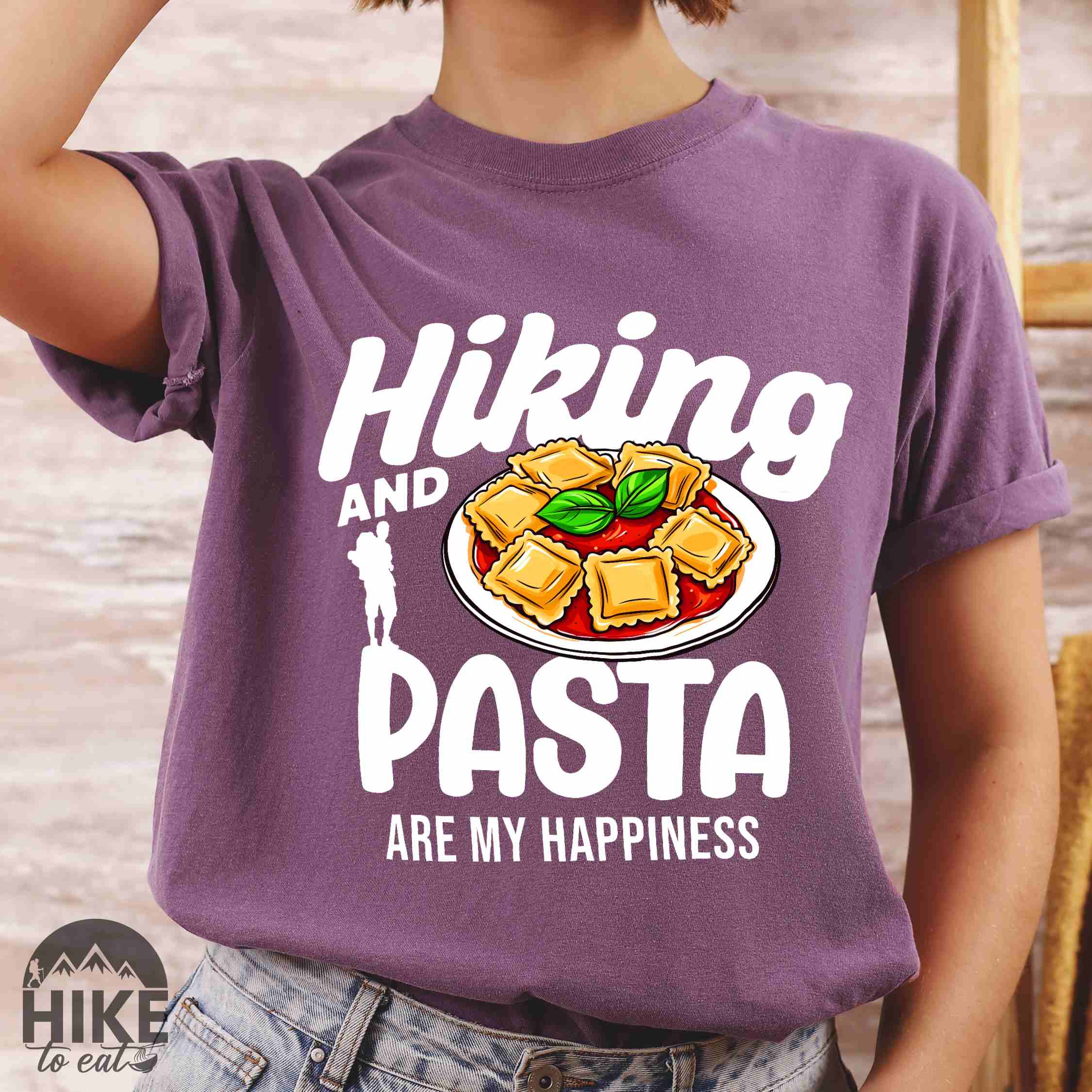 Woman wearing berry "Hiking and pasta are my happiness" colored vintage tee with bold typography, illustrated plate of pasta, and backpackers for pasta lovers.