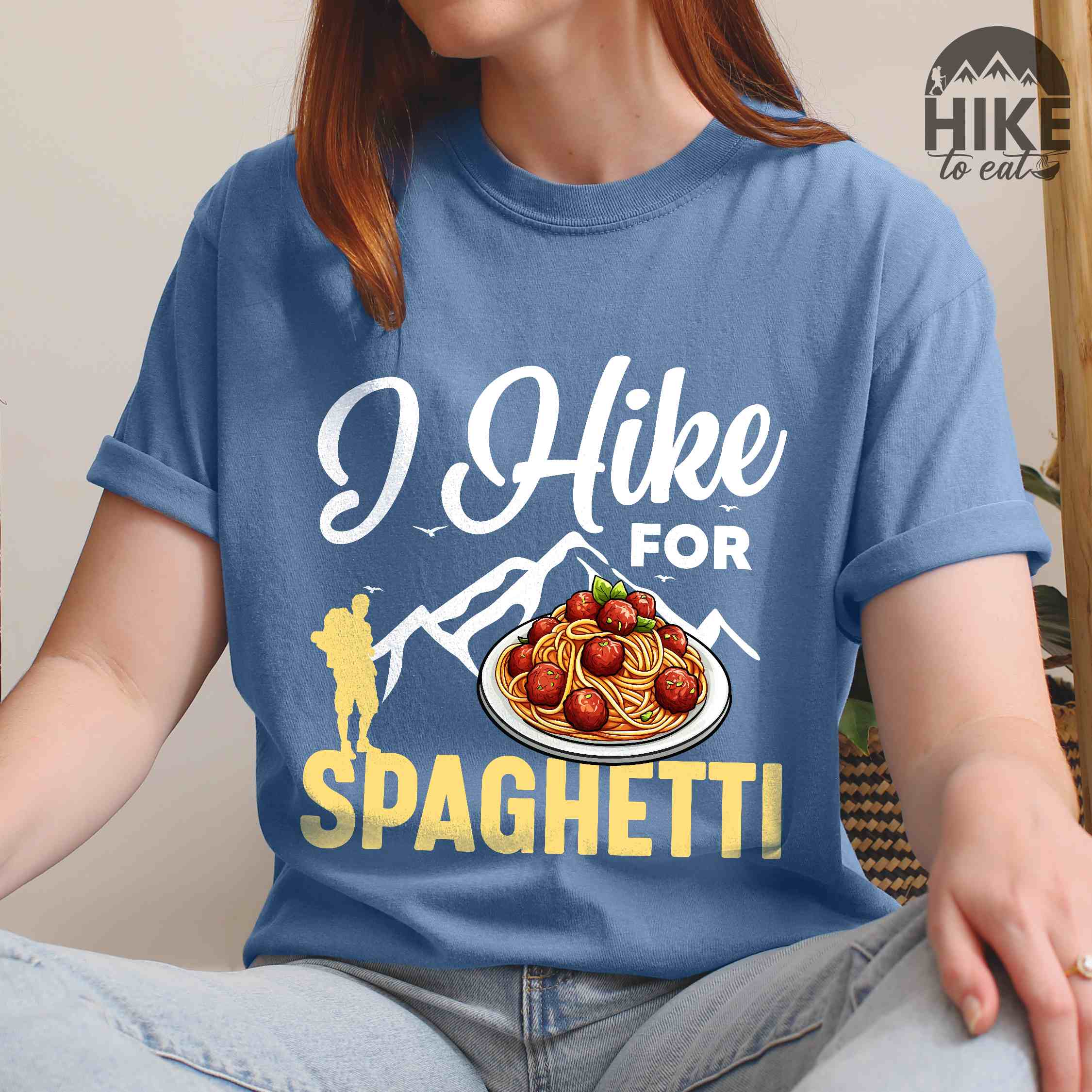 Woman wearing blue jean "I hike for spaghetti" colored vintage tee with bold typography, illustrated plate of spaghetti meatballs, and backpackers for pasta lovers.