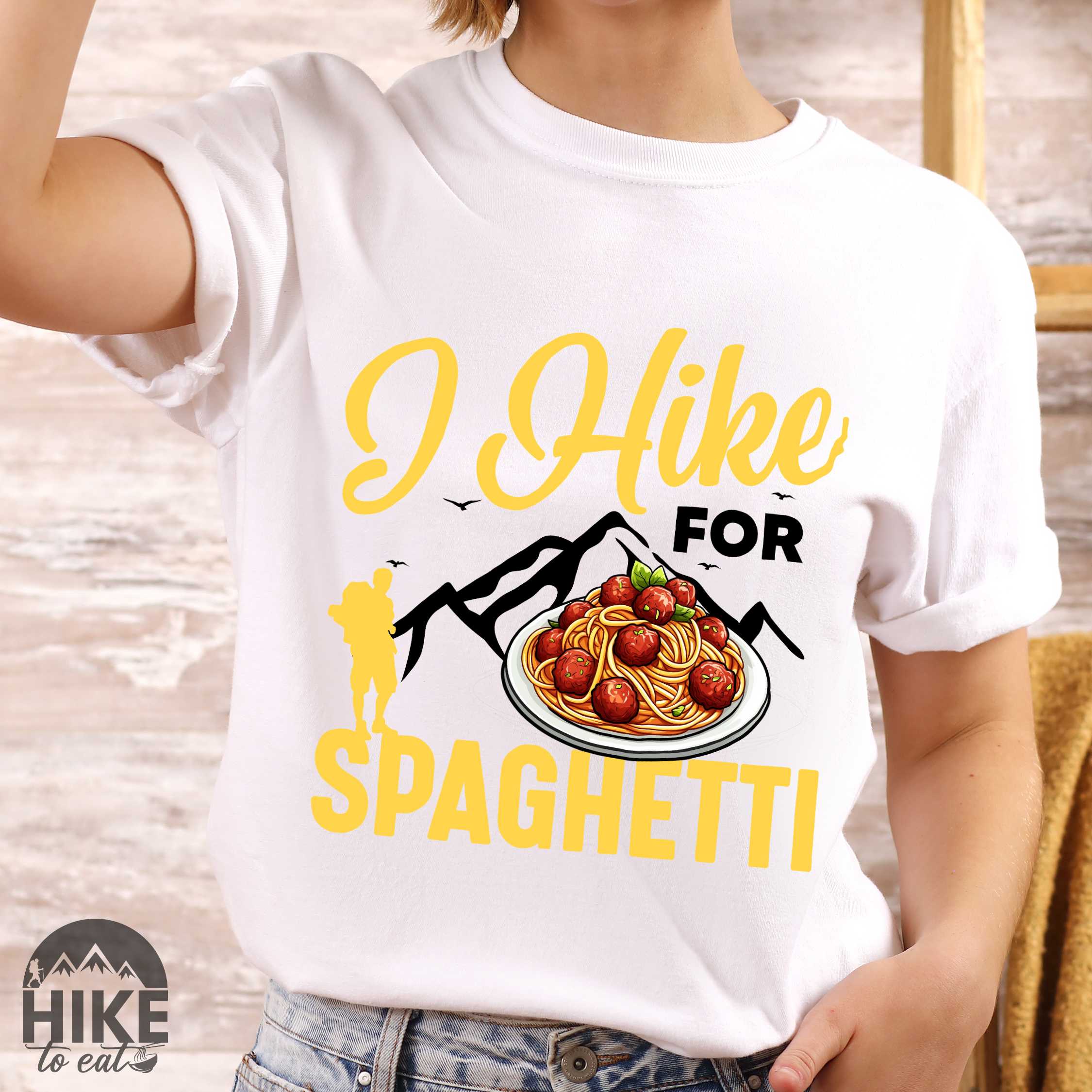 Woman wearing white "I hike for spaghetti" colored vintage tee with bold typography, illustrated plate of spaghetti meatballs, and backpackers for pasta lovers.