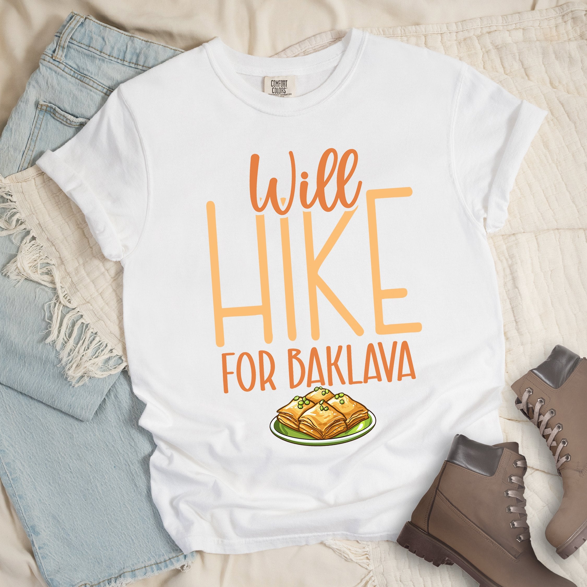 White t -shirt with Hiking Design featuring the phrase “Will Hike for Baklava” and an illustration of baklava on a plate.