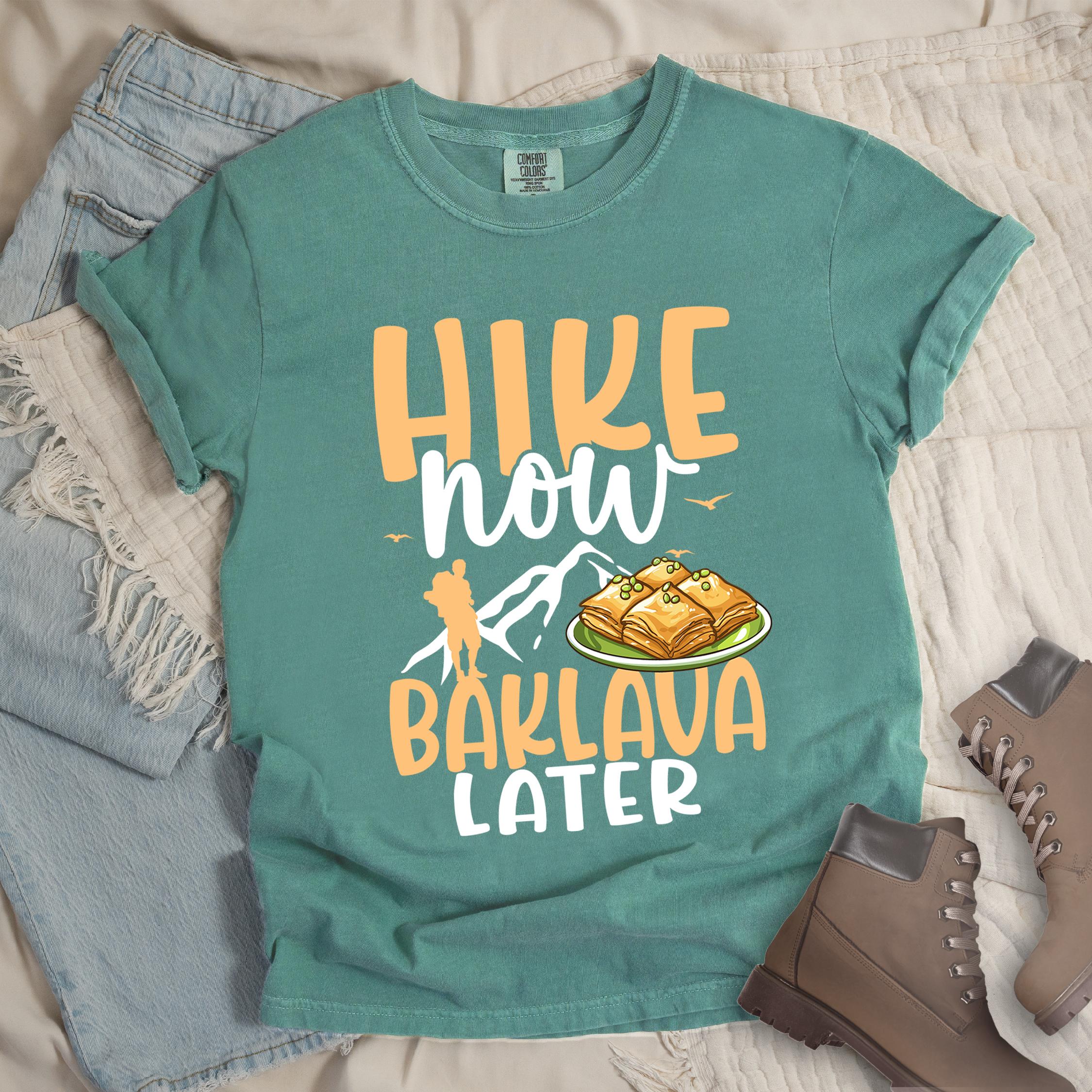 Green shirt with Hiking Design featuring the phrase “Will Hike for Baklava” in bold lettering and a colorful illustration of golden baklava on a plate.