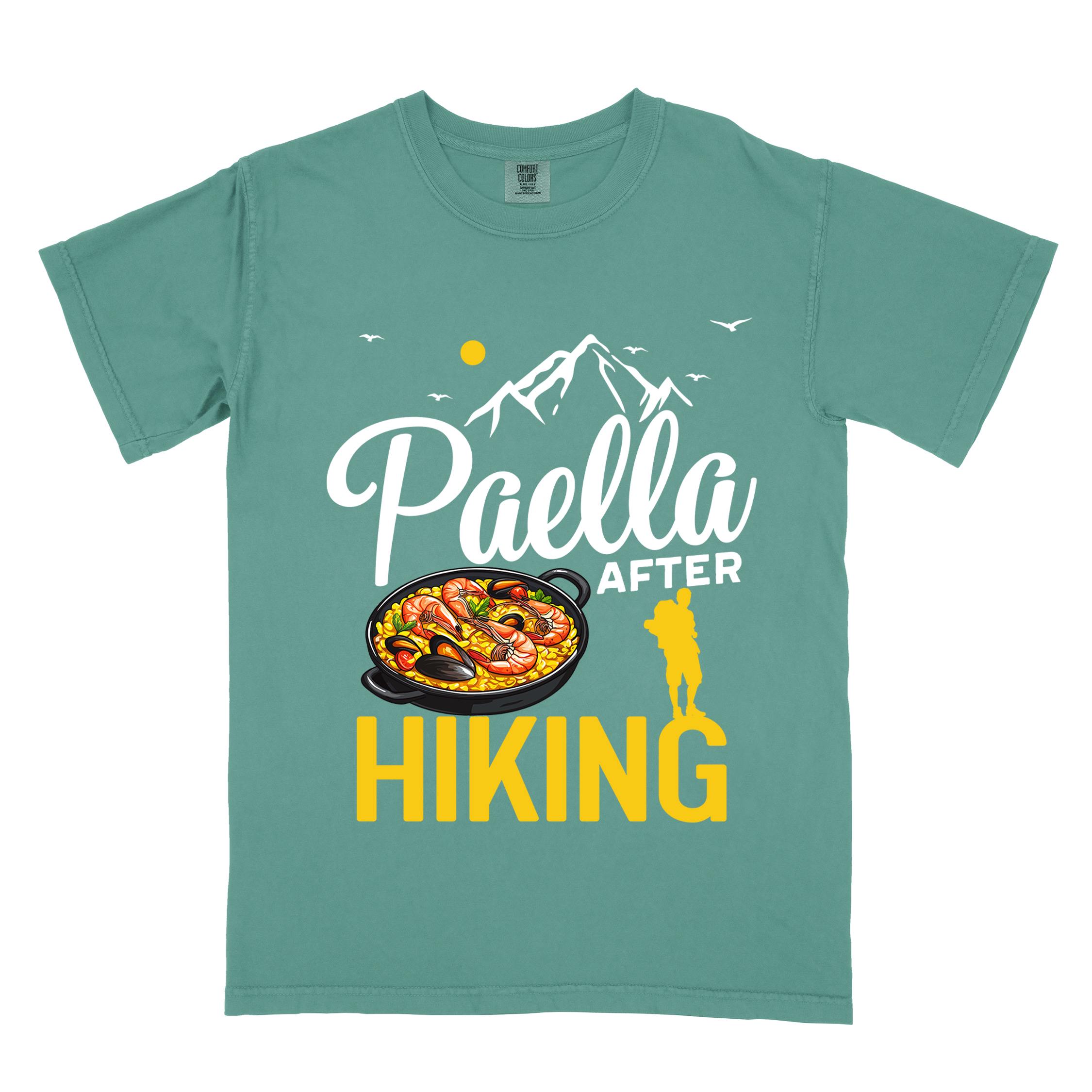 Light green "Paella after hiking" colored vintage tee with bold typography, mountains, birds, illustrated paella platter, and backpackers for rice lovers.