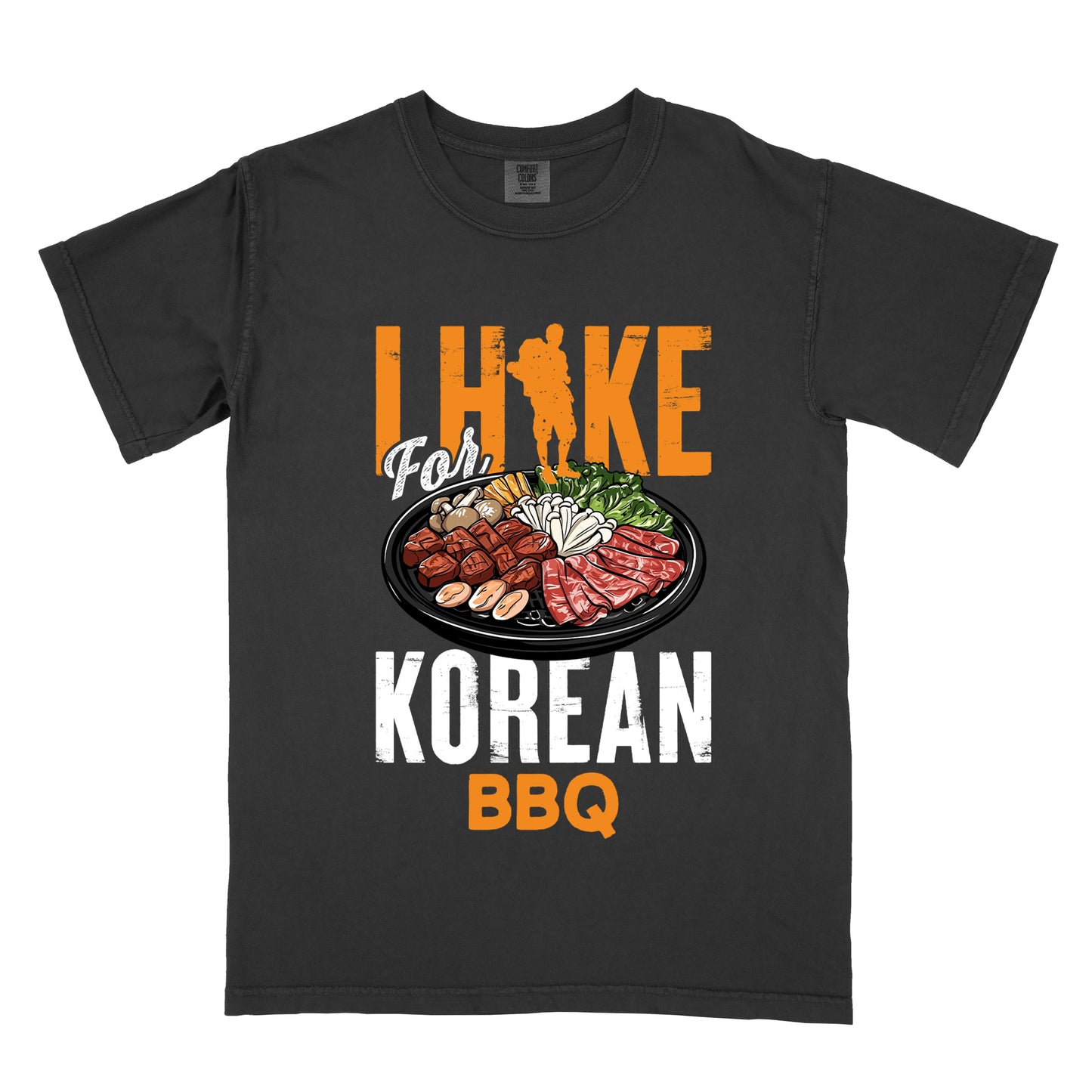 Black t-shirt with orange and white text reading "I HIKE For KOREAN BBQ". "I HIKE" appears in large distressed orange letters at the top with a hiker silhouette integrated into the letter "I", "For" in white script in the middle, "KOREAN" in large distressed white letters, and "BBQ" in orange at the bottom. Features a detailed illustration of Korean barbecue with meat, mushrooms, and vegetables on a black plate in between "For" and "KOREAN." 