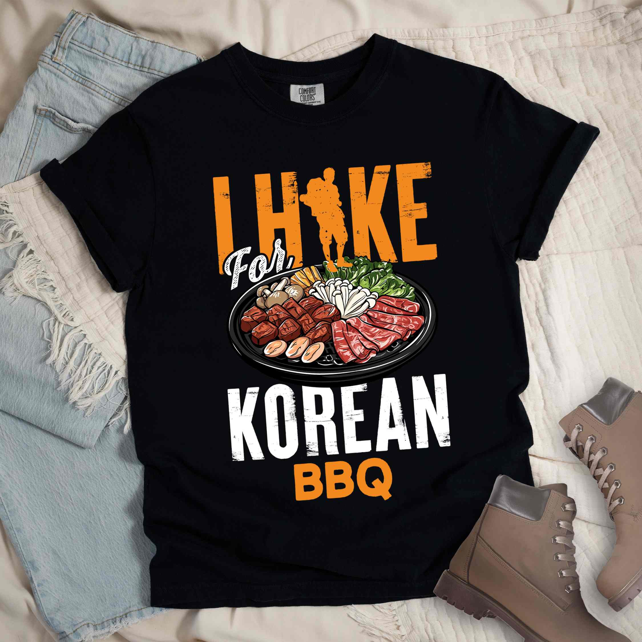 Black "I hike for korean bbq" colored vintage tee with bold typography, illustrated grilling platter korean bbq, mountains, birds, and backpacker for kbbq lovers.