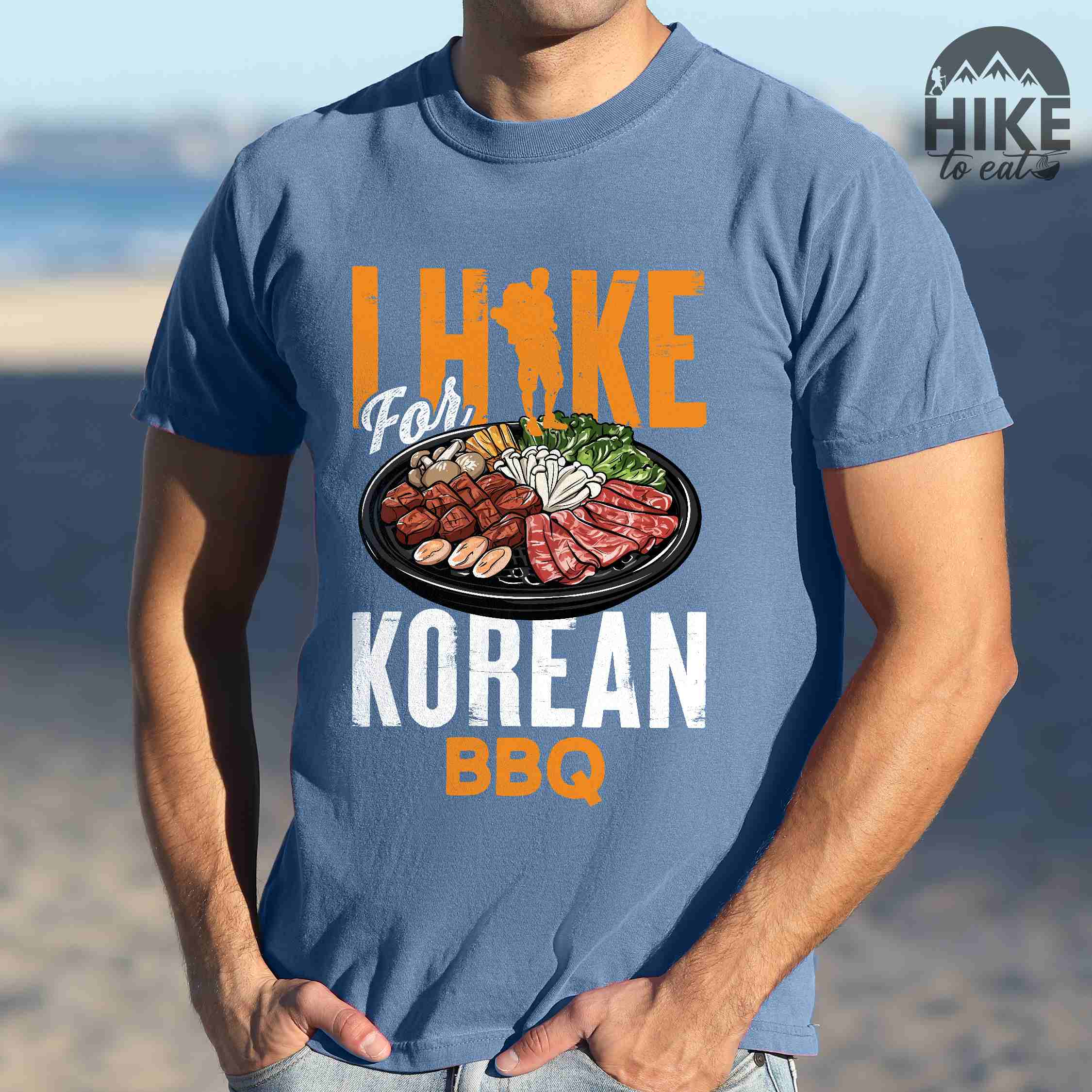 Blue jean "I hike for korean bbq" colored vintage tee with bold typography, illustrated grilling platter korean bbq, mountains, birds, and backpacker for kbbq lovers.