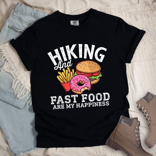 Black shirt showing a hiking design with 'Hiking and fast food are my happiness' phrase and an illustration of fast food meal in front. 