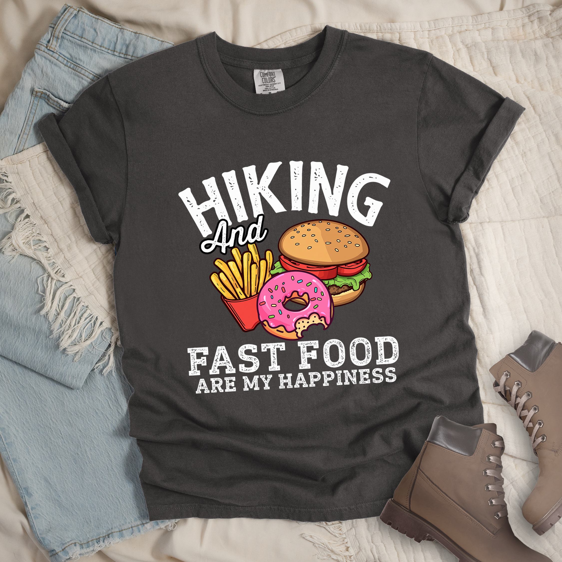 Dark grey shirt showing a hiking design with 'Hiking and fast food are my happiness' phrase and an illustration of fast food meal in front. 