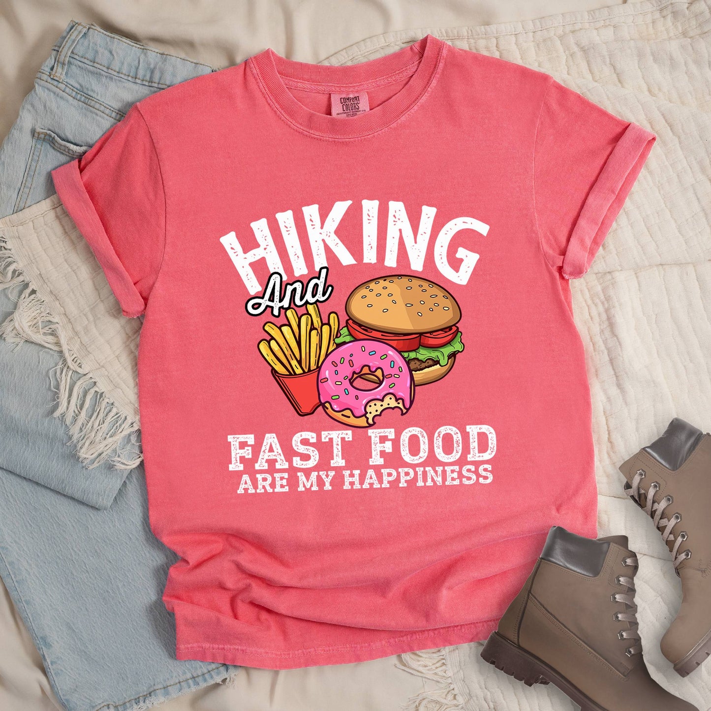 Pink shirt showing a hiking design with 'Hiking and fast food are my happiness' phrase and an illustration of fast food meal in front. 