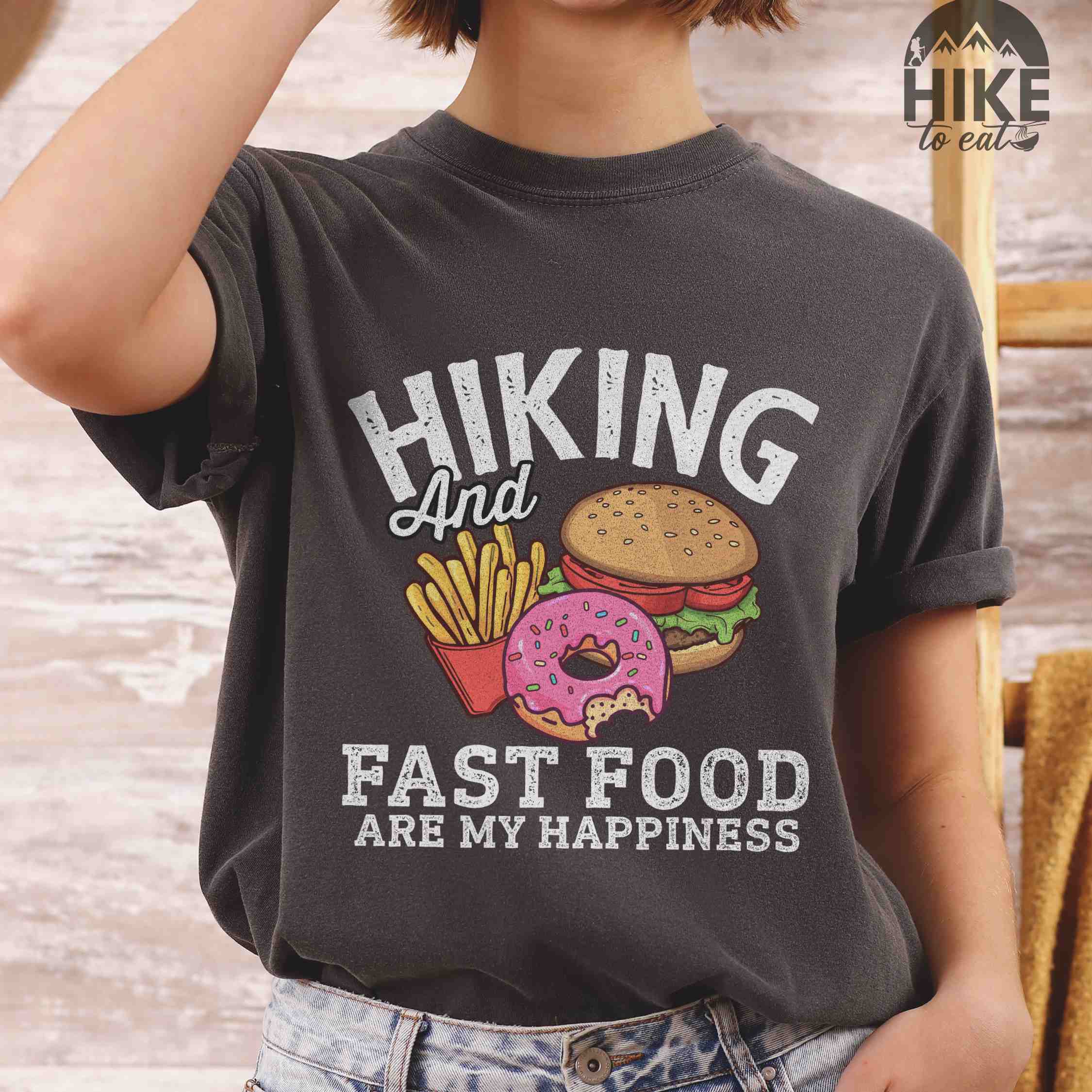 Woman wearing pepper "Hiking and Fast Food are my Happiness" colored vintage tee with bold typography, and illustrated fast food meal for the hikers who wants a rewarding meal.