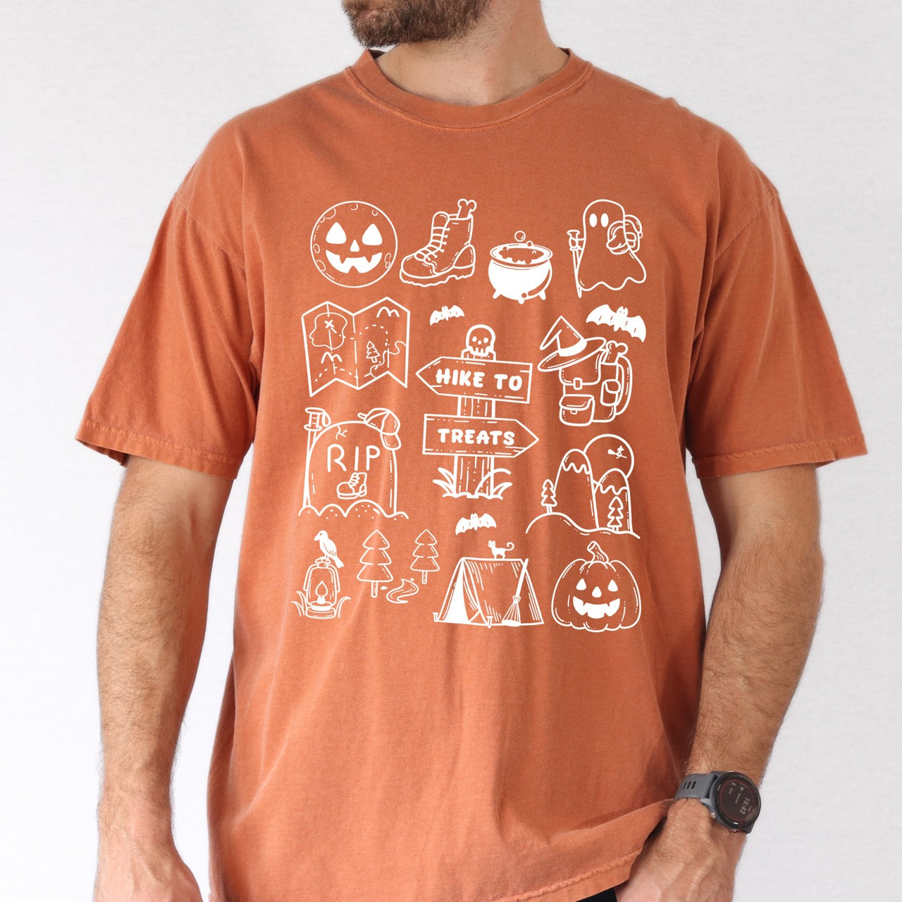 Man wearing Yam Halloween adventure vintage tee featuring illustrated icon collection with jack-o-lantern boots cauldron ghost backpacker map RIP tombstone Hike to Treats trail sign tent pumpkin bats and trees on Comfort Colors shirt for spooky season celebrations for hikers, foodies and adventurers
