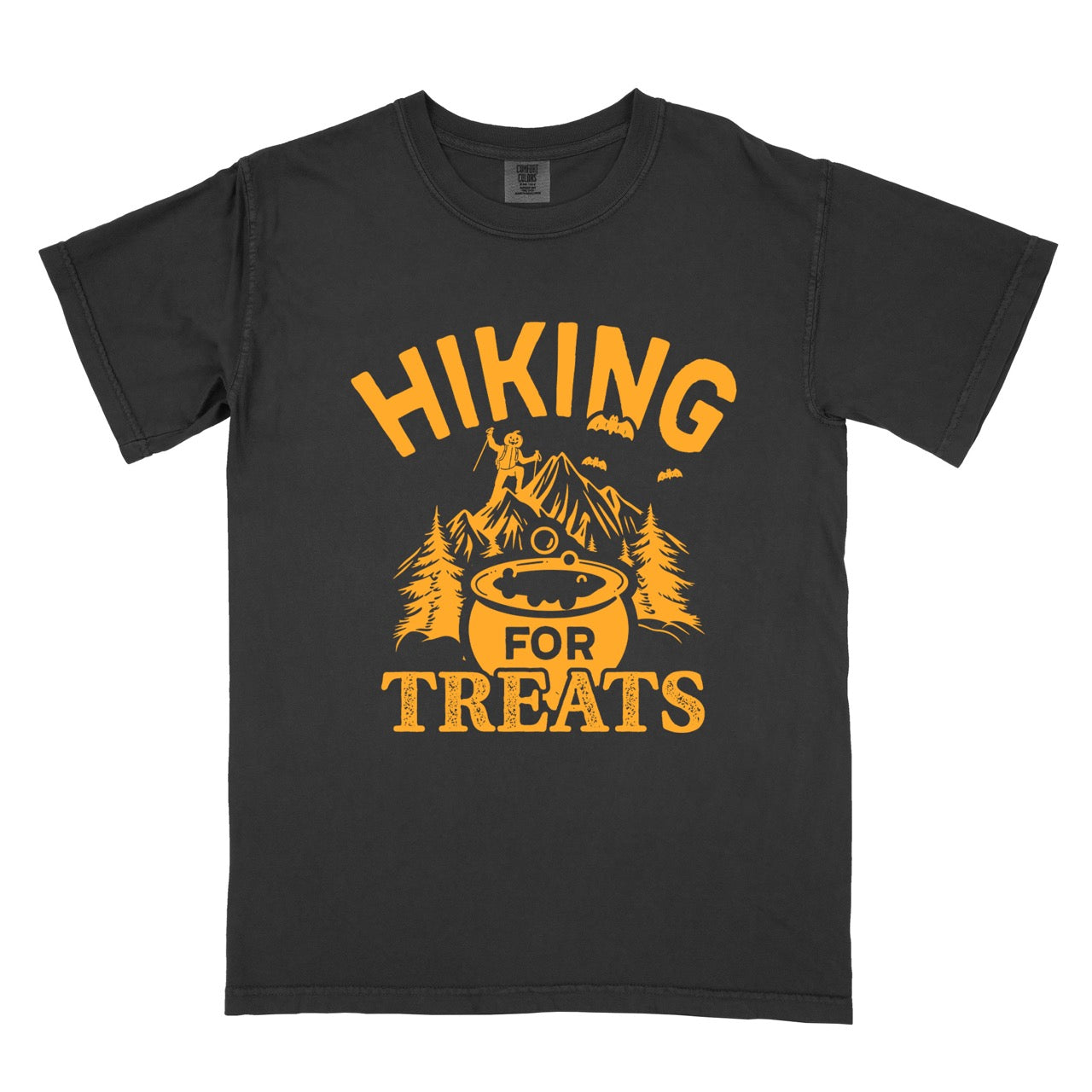 Black Halloween vintage tee Hiking for Treats featuring curved typography bubbling cauldron with candy mountain landscape with character on peak pine trees and flying bats on Comfort Colors shirt for spooky season celebrations for hikers, foodies and adventurers. 